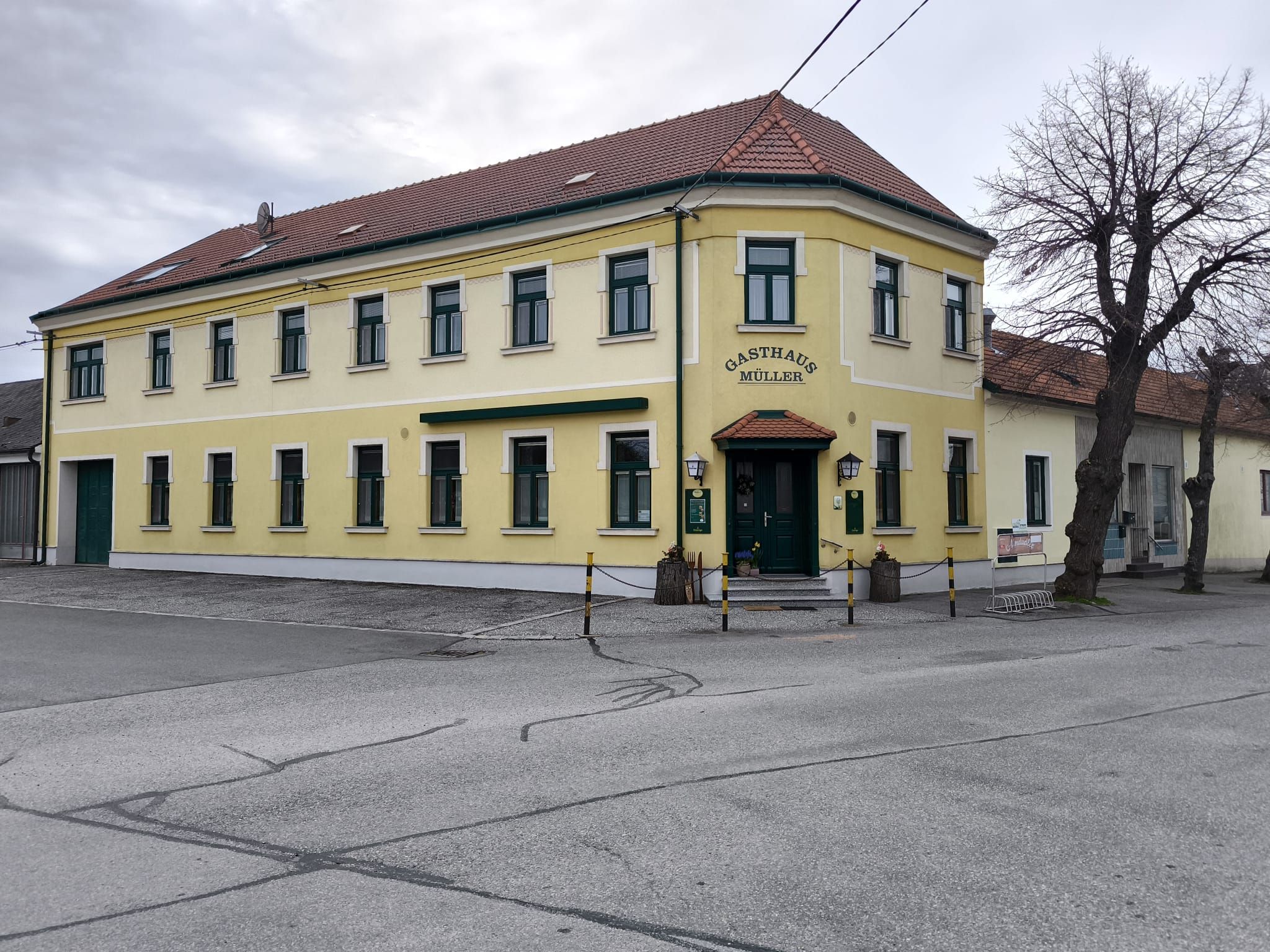 Žltá dvojposchodová budova s nápisom "Gasthaus Müller".