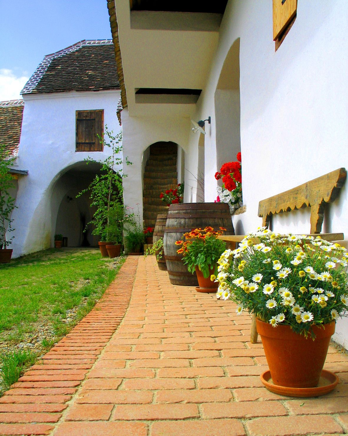 Tradičné nádvorie s kvetmi a drevenými sudmi.