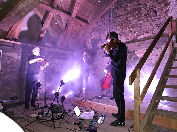 Hudobníci hrajú v rustikálnom podkroví so svetelnými efektmi.