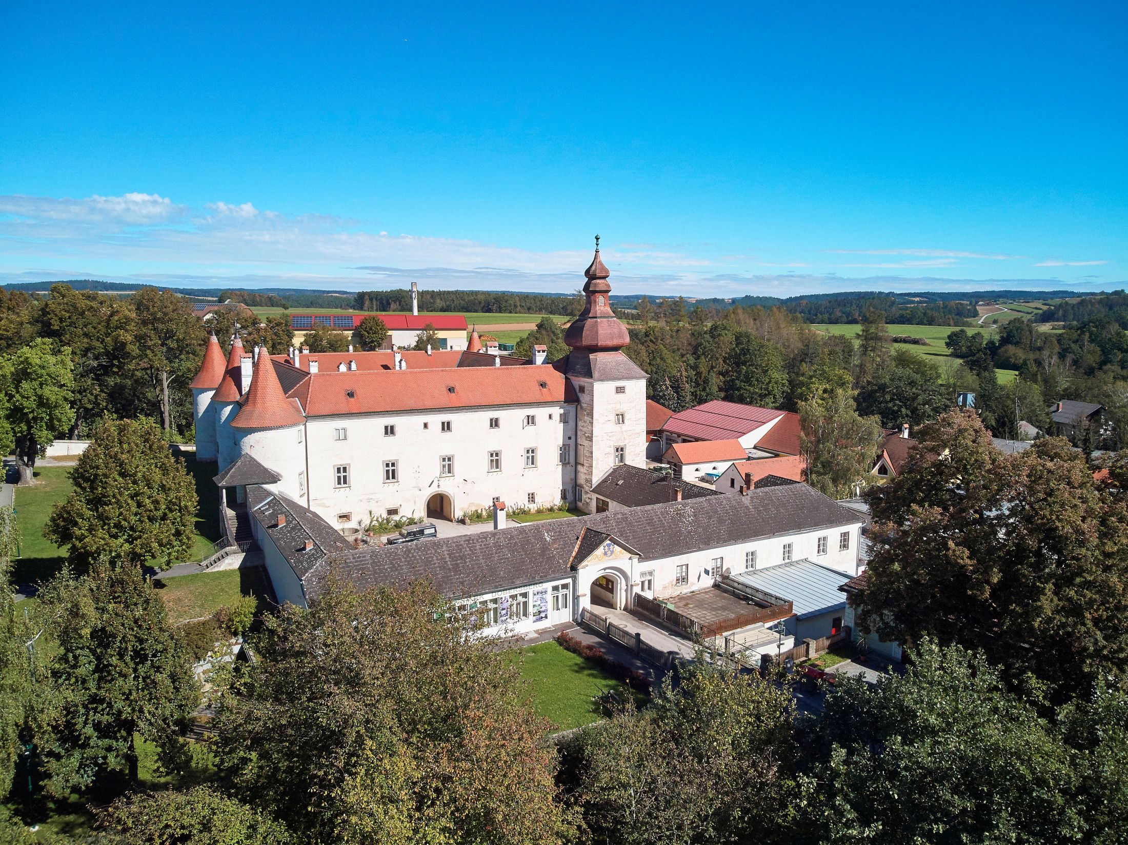 Letecký pohľad na hrad Dobersberg s červenou strechou a okolitú krajinu.