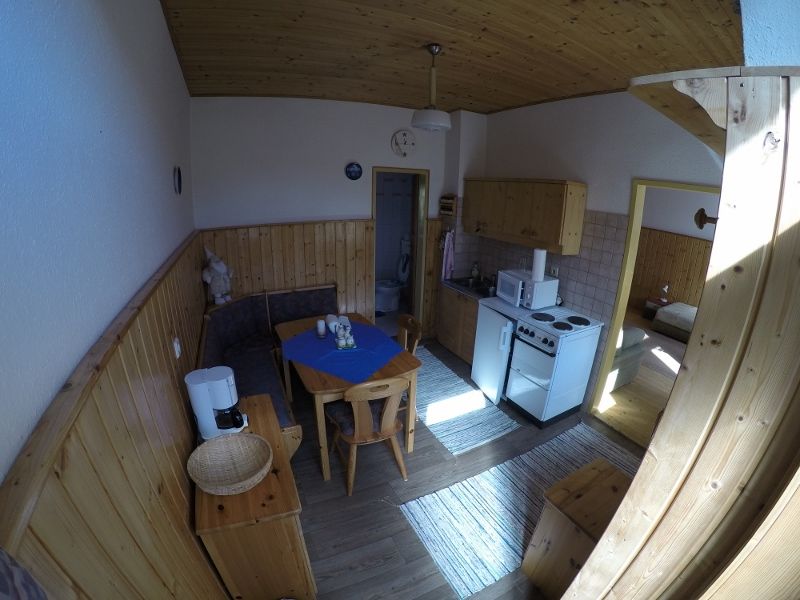 Kuchyňa-obývacia izba v prázdninovom byte s dreveným nábytkom, jedálenským stolom, kuchynským kútom a prístupom do spálne.