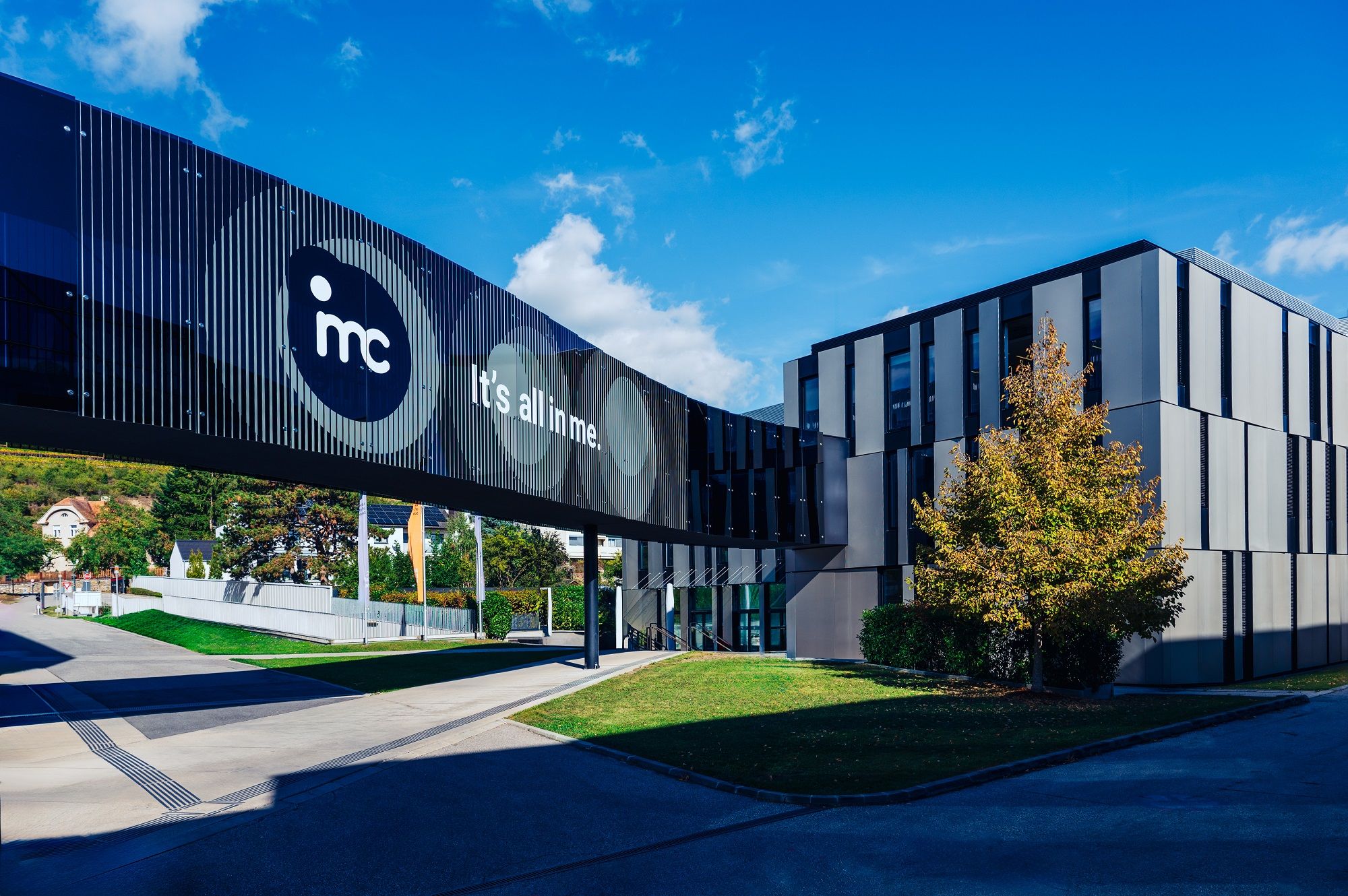 Moderná budova IMC Krems so skleneným mostom a nápisom "It's all in me".