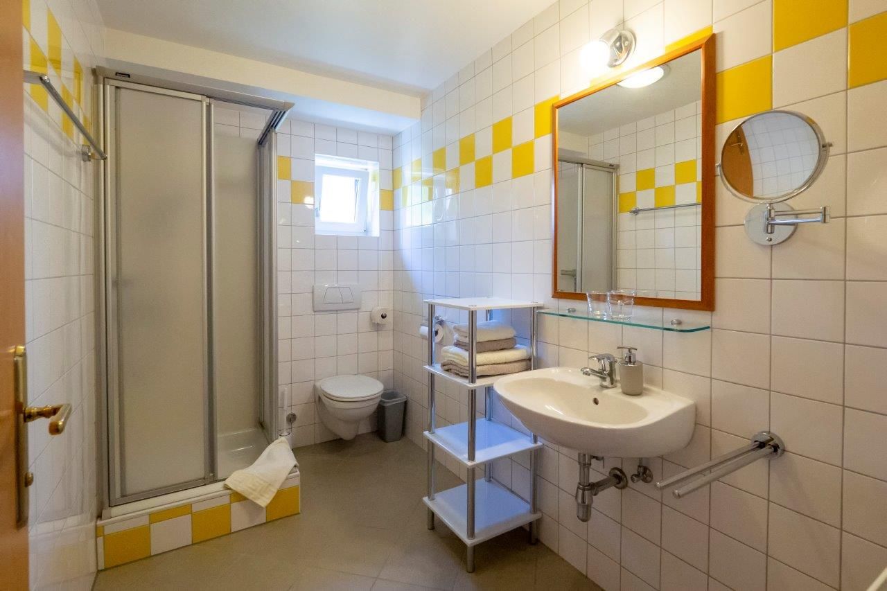 Kúpeľňa so sprchovacím kútom, WC, umývadlom a zrkadlom.