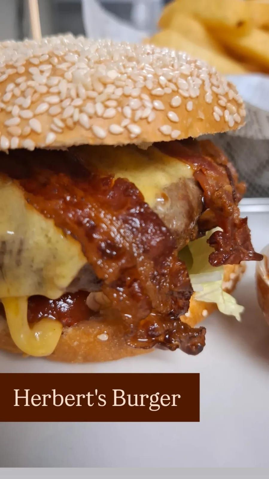 Detailný záber na hamburger so sezamovou žemľou, roztaveným syrom a chrumkavou slaninou.