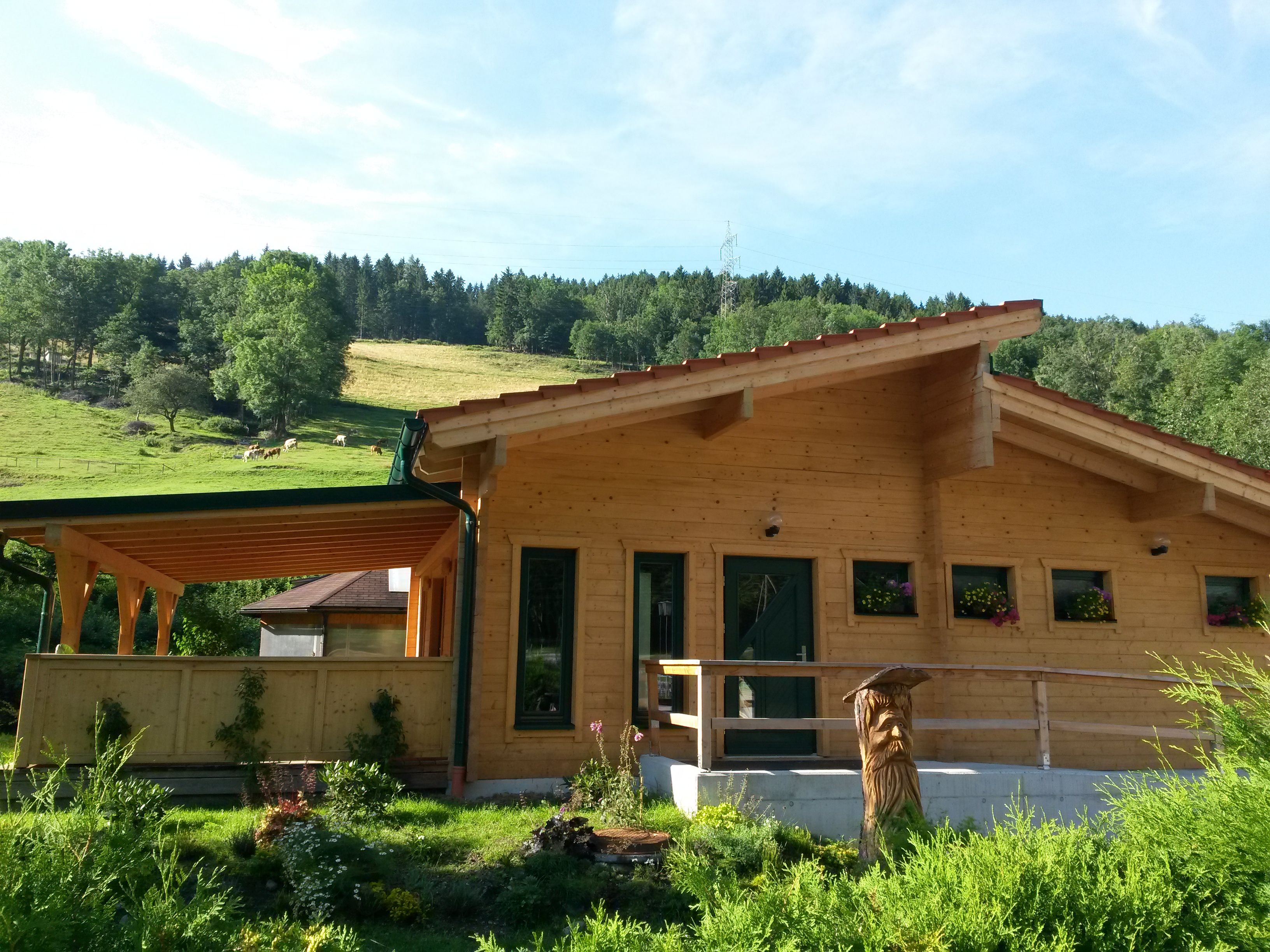 Zrubová sauna vo vidieckom prostredí s drevenou verandou a kvetinovými truhlíky.