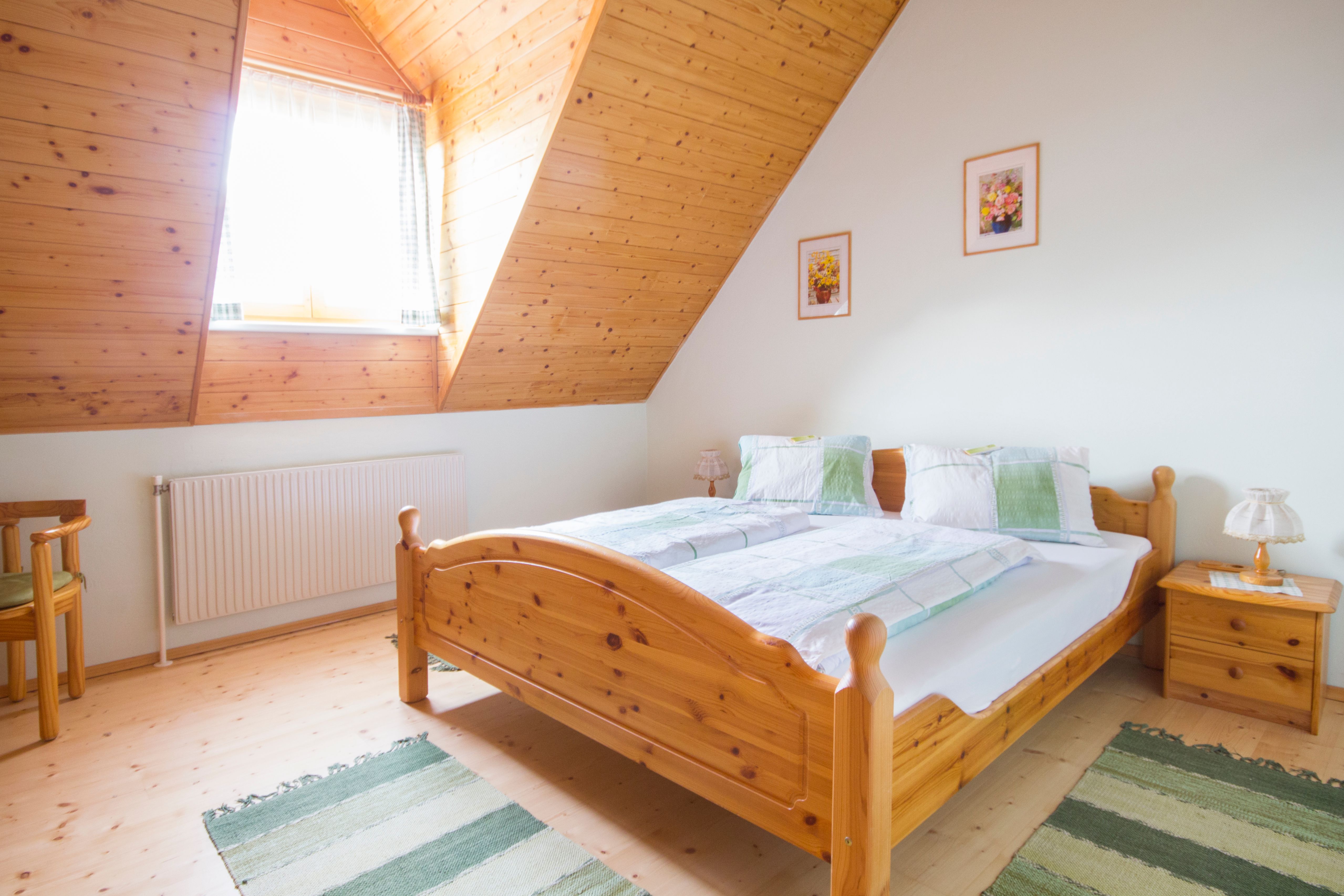 Útulná spálňa s dreveným nábytkom a šikmým stropom.