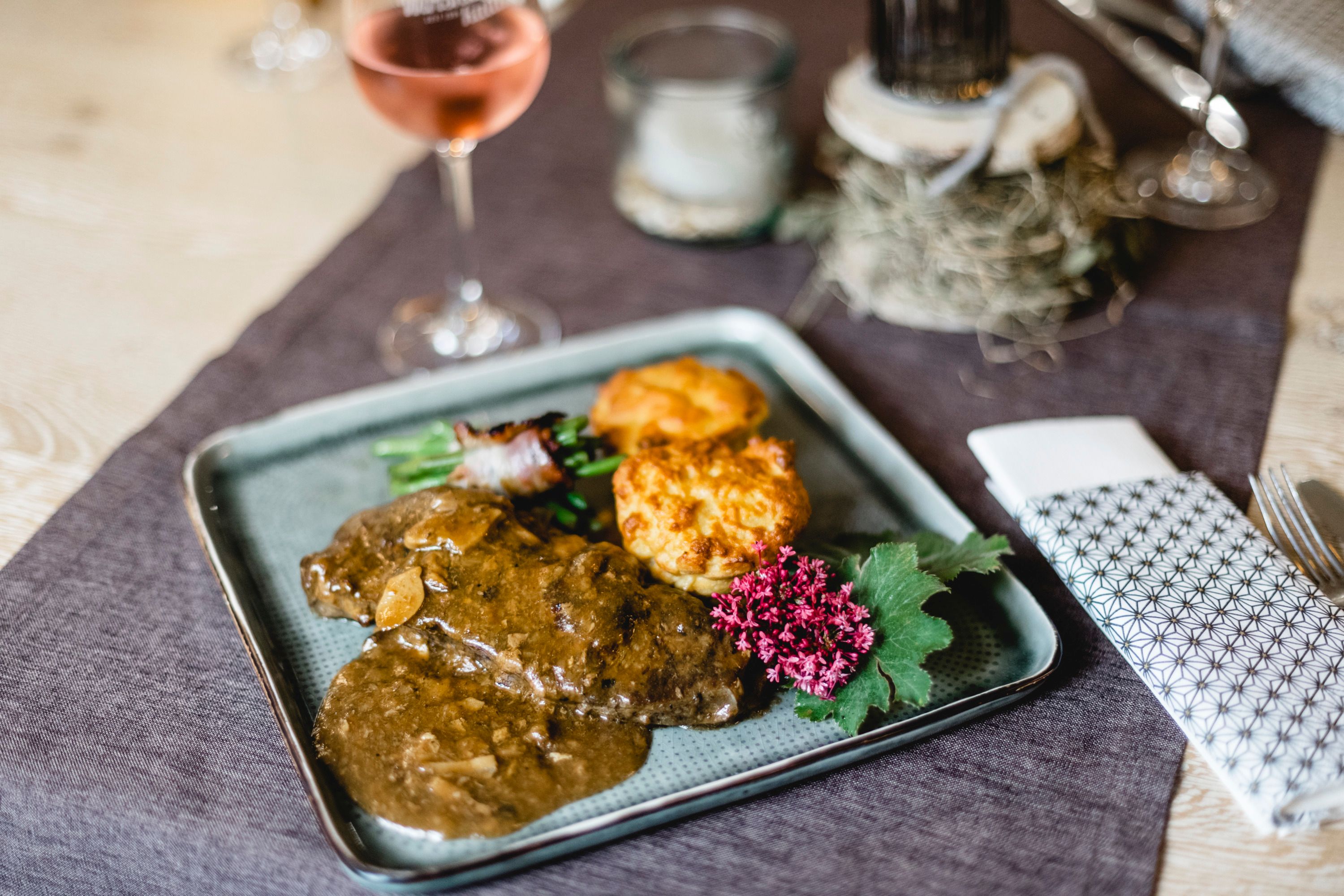 Hovädzia pečienka plnená šampiňónmi, podávaná s prílohami a kvetom na ozdobu.