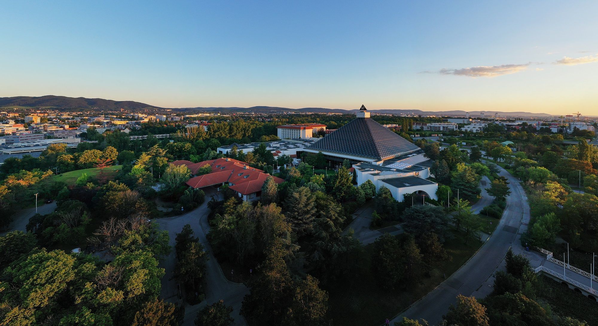 Letecký pohľad na Eventhotel Pyramide s okolitou krajinou pri západe slnka.