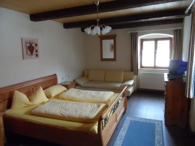 Útulná dvojlôžková izba s drevenou posteľou, pohovkou a oknom.