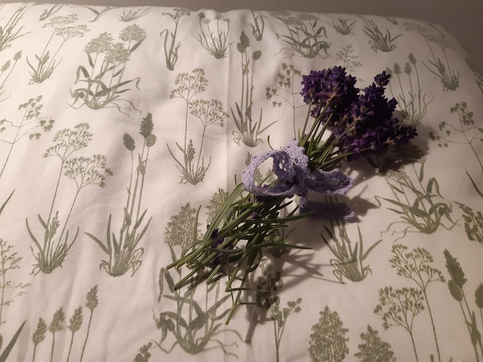 Na vankúši s rastlinným vzorom leží zväzok levandule.
