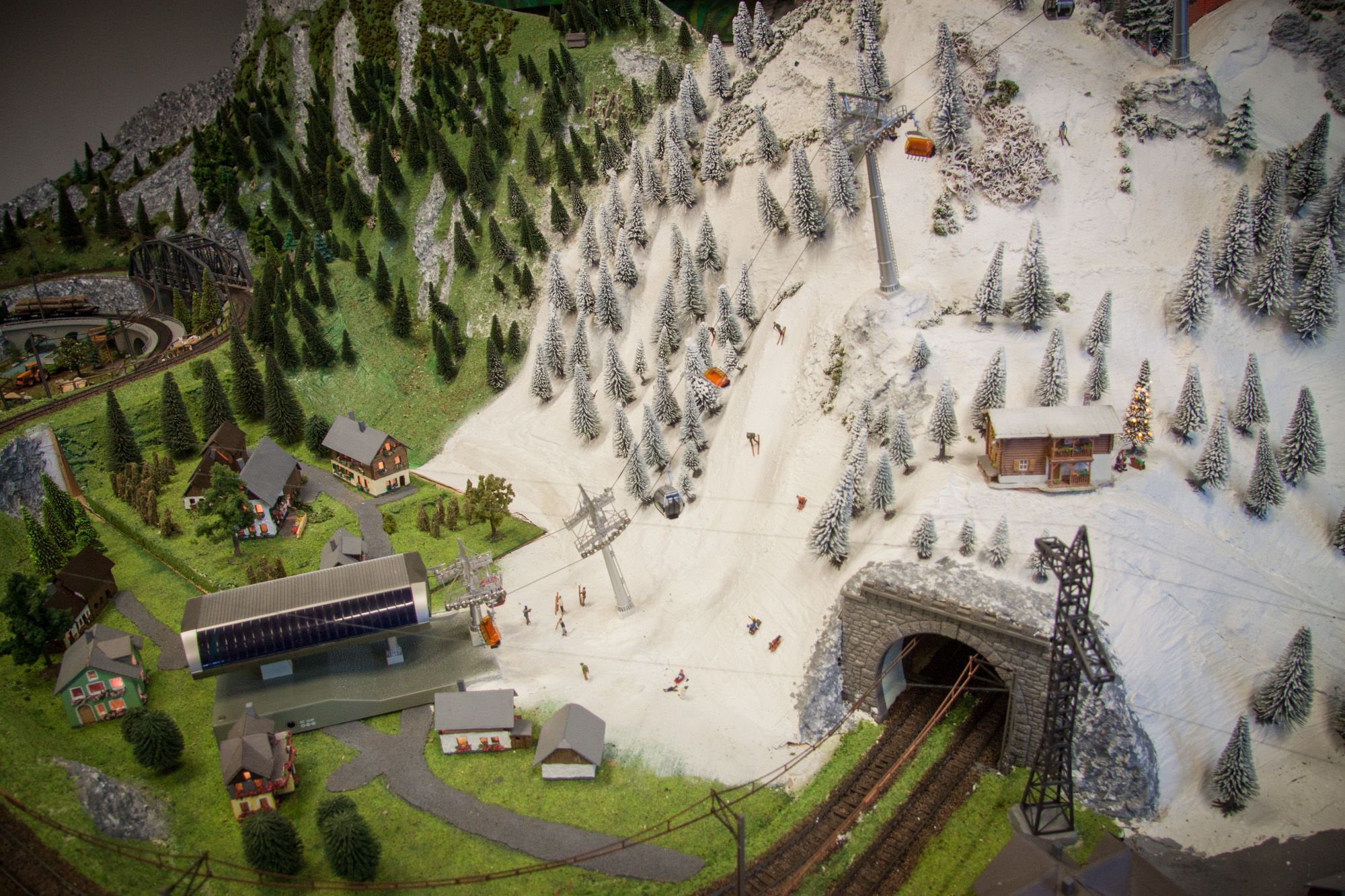 Model krajiny s horami, lyžiarmi, lanovkou a železničným tunelom.