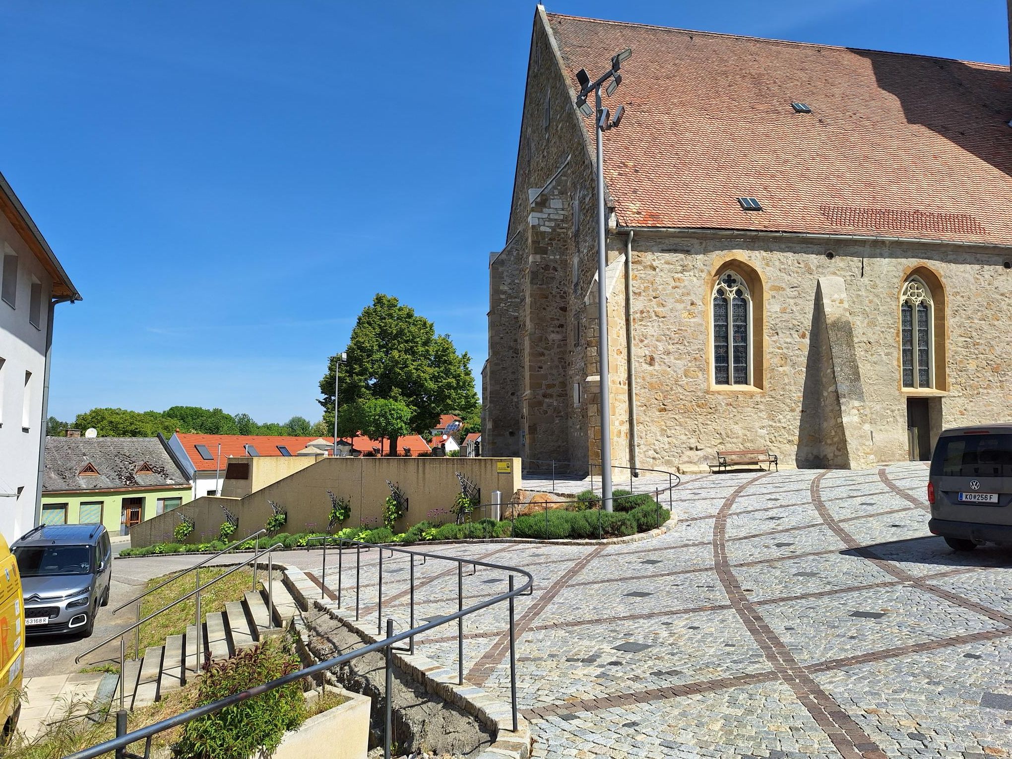 Kamenné schodisko vedie do historickej budovy s červenou škridlovou strechou a gotickými oknami.
