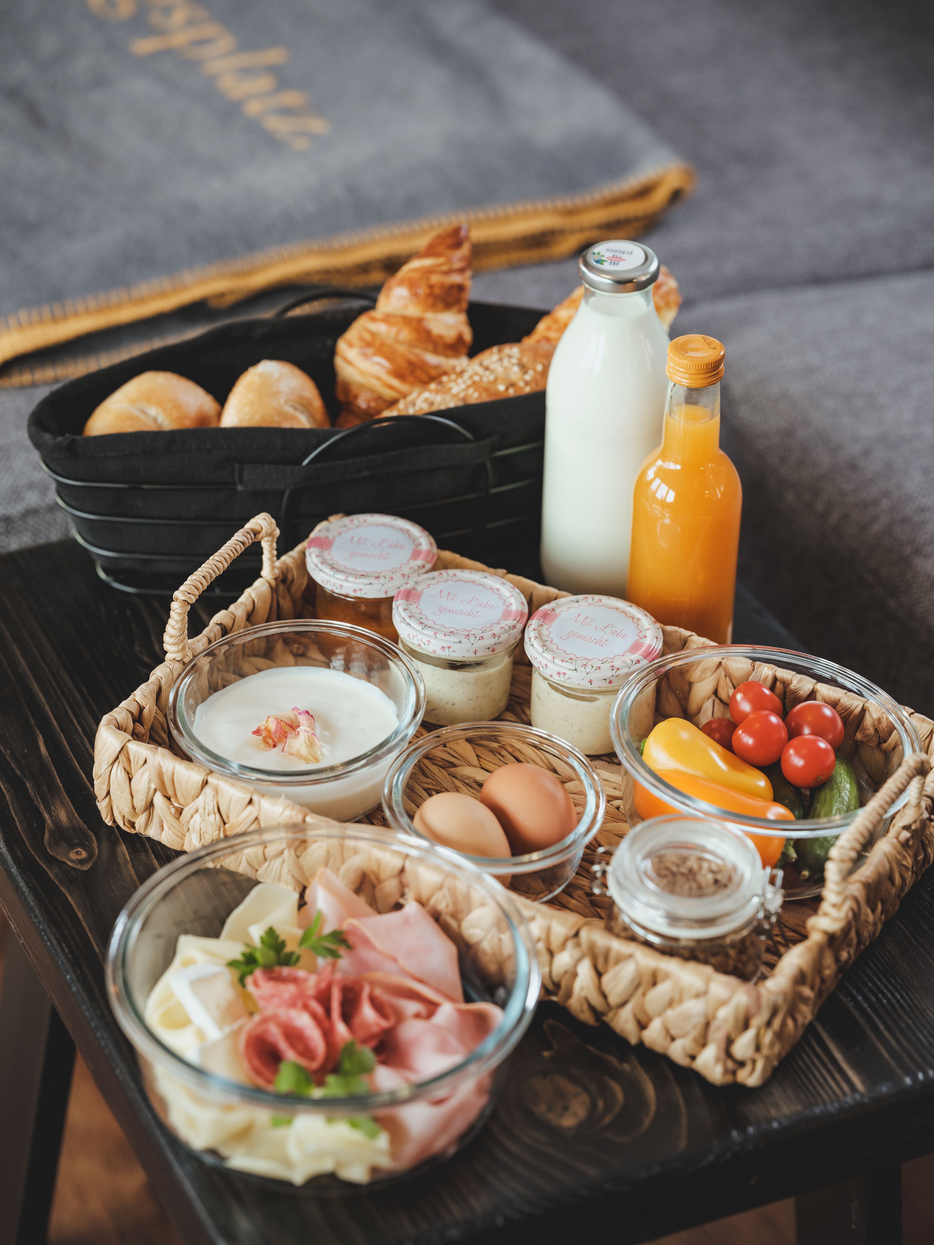 Raňajkový podnos s chlebom, croissantom, mliekom, džúsom, jogurtom, vajíčkami, údeninami a zeleninou.