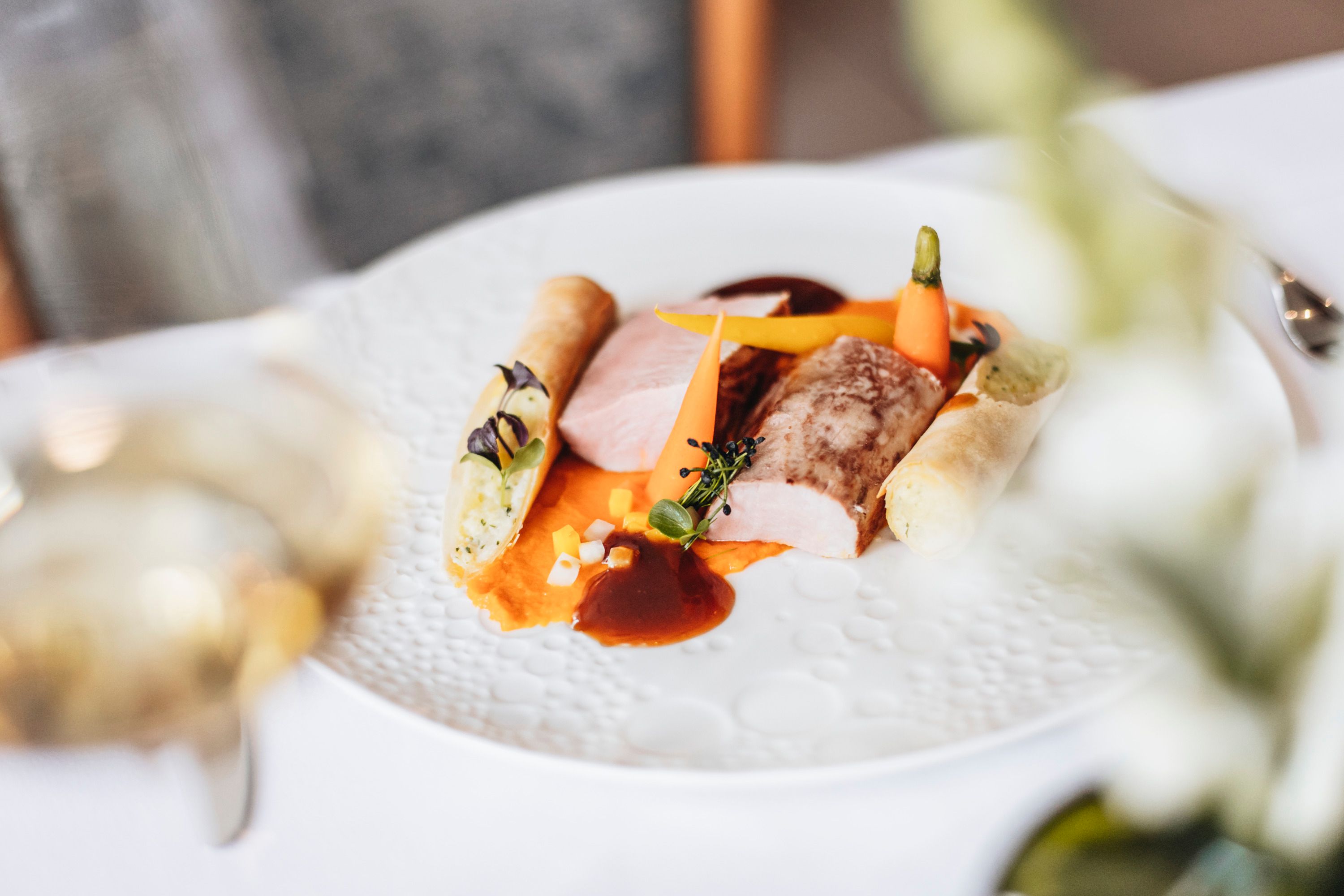 Gurmánske jedlo s bravčovým filé, zeleninou a zemiakovou rolkou na bielom tanieri.