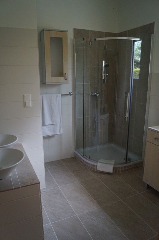 Moderná kúpeľňa so sprchovacím kútom, umývadlom a uterákom.