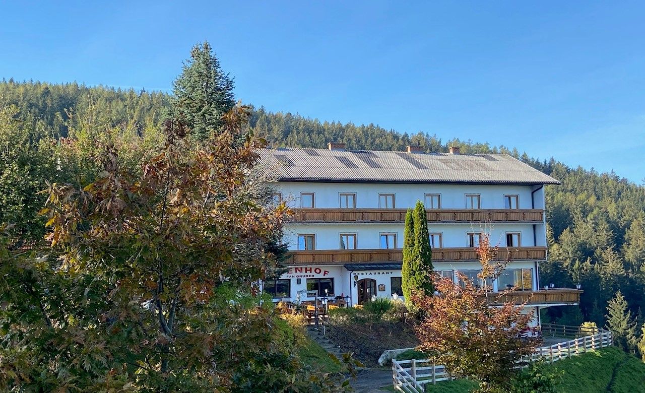Gasthof-Pension Ödenhof pred zalesneným kopcom.
