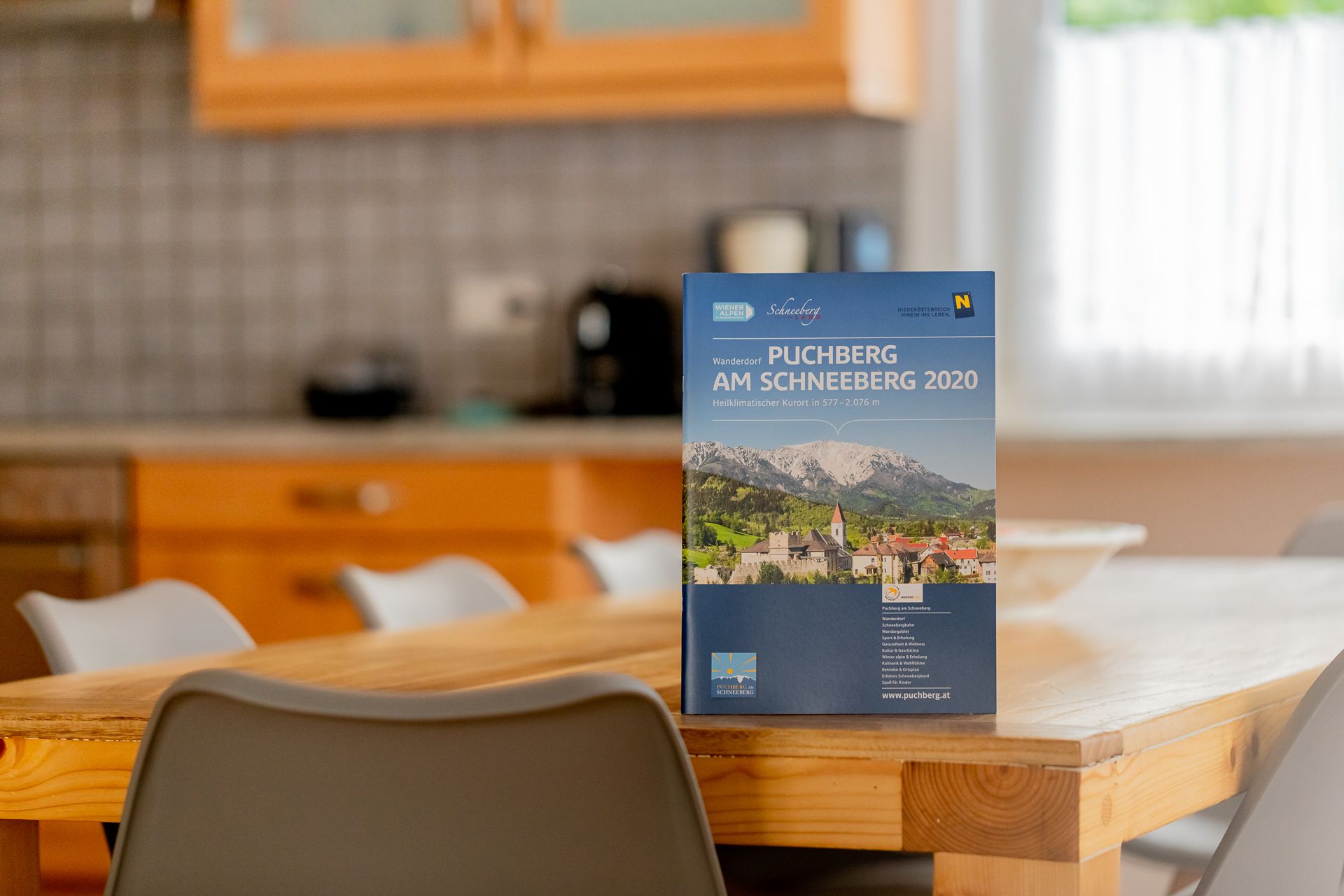 Na drevenom stole v kuchyni stojí brožúra o meste Puchberg am Schneeberg.