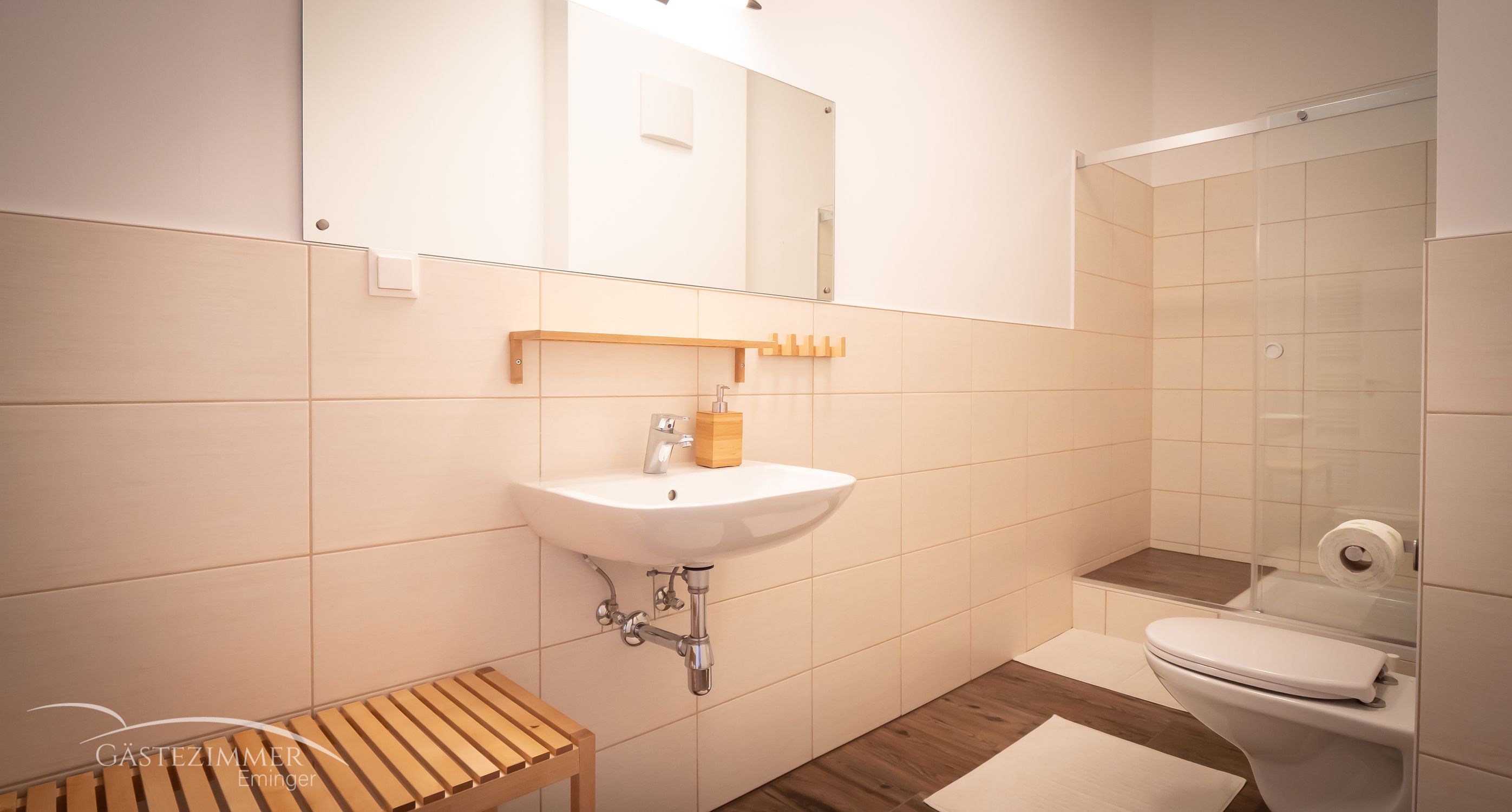 Moderná kúpeľňa s umývadlom, zrkadlom, sprchovacím kútom a WC.