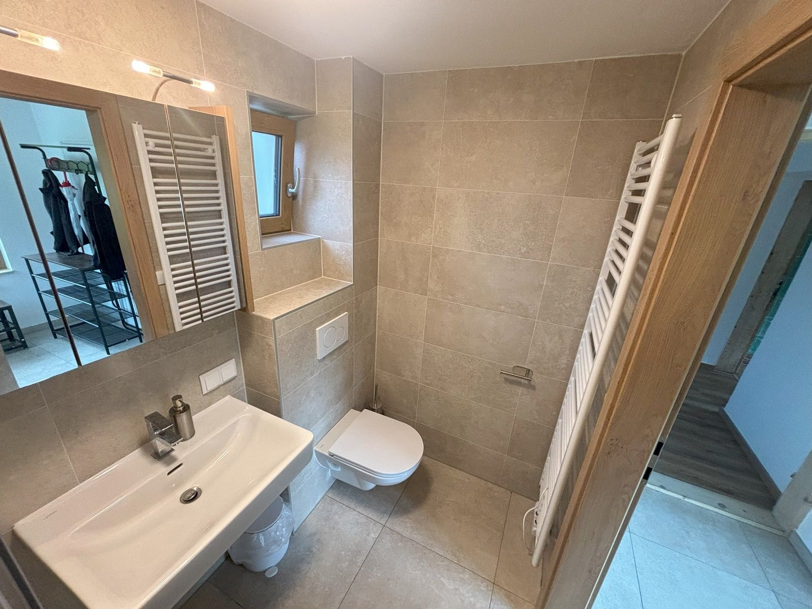 Moderná kúpeľňa s umývadlom, WC a radiátorom na uteráky.