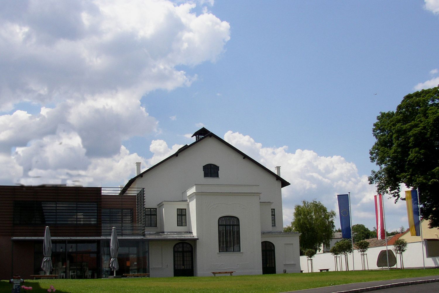 Koncertná sieň Ziersdorf s modernou prístavbou a vlajkami v popredí.