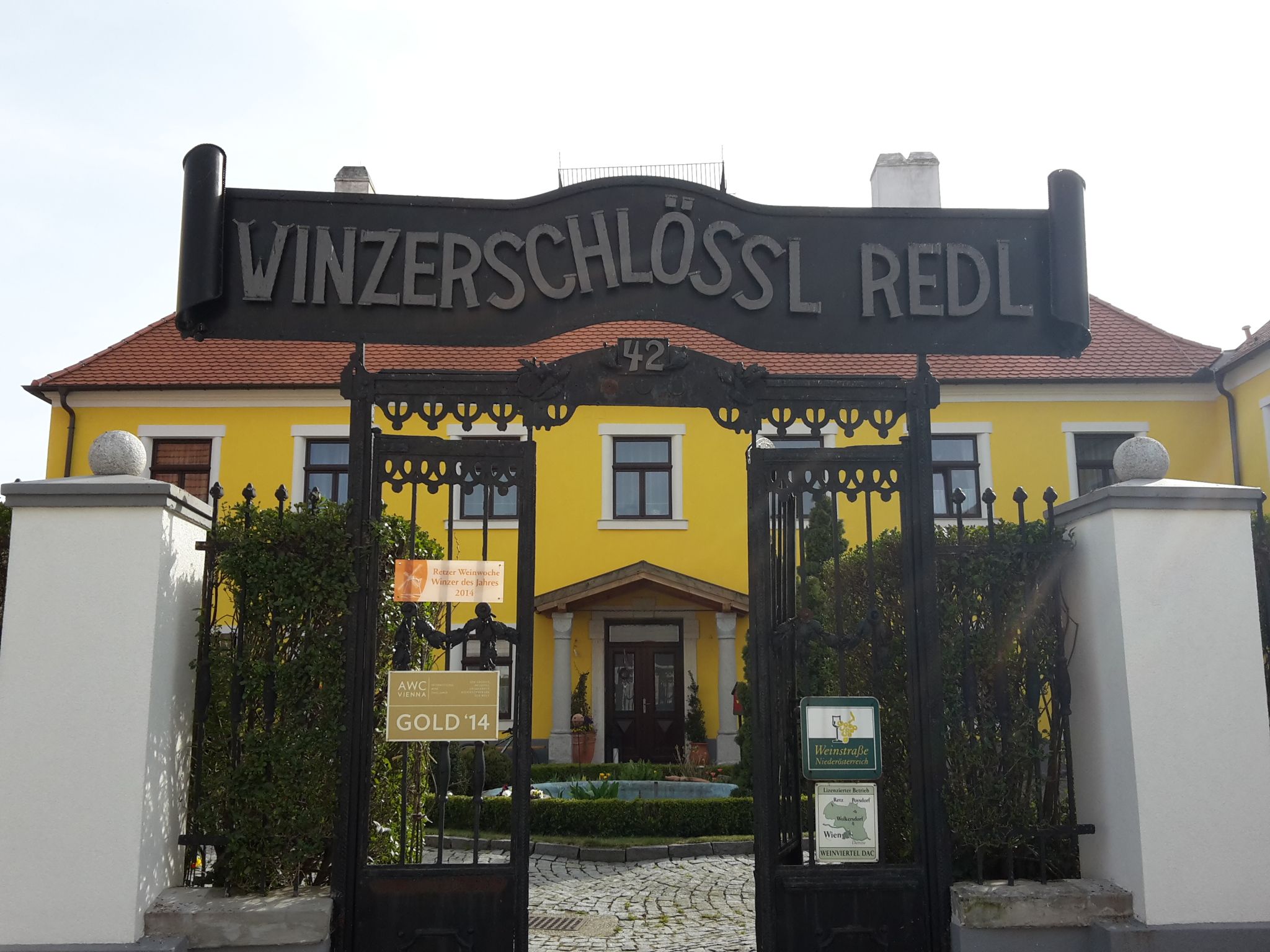 Vstupná brána do obce Winzerschlössl Redl so žltou budovou v pozadí.