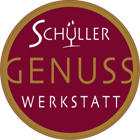 Logo Schüller Genuss Werkstatt s červeným pozadím a zlatým písmom.