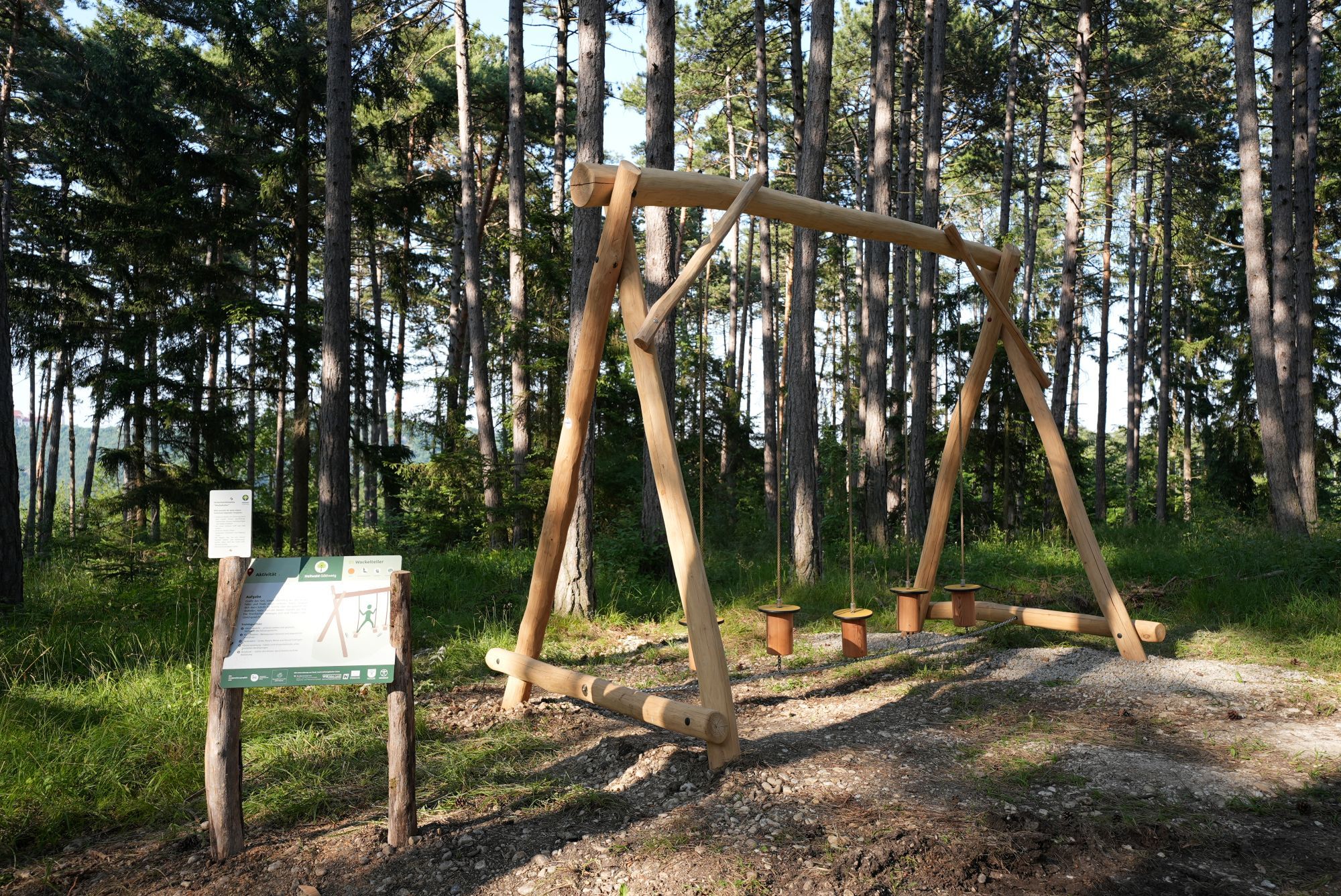 Drevené zariadenie v lese s informačnou tabuľou v liečivom lese Göttweig.