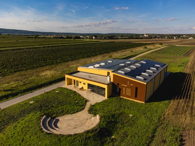 Letecký pohľad na moderné vinárstvo so solárnymi panelmi, obklopené vinicami a poliami.