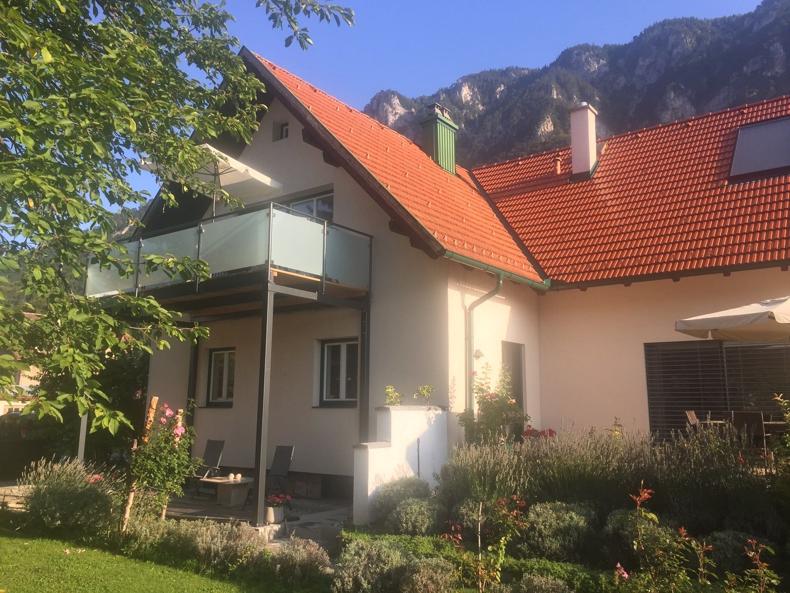 Rekreačný dom s balkónom a záhradou na pozadí hôr.