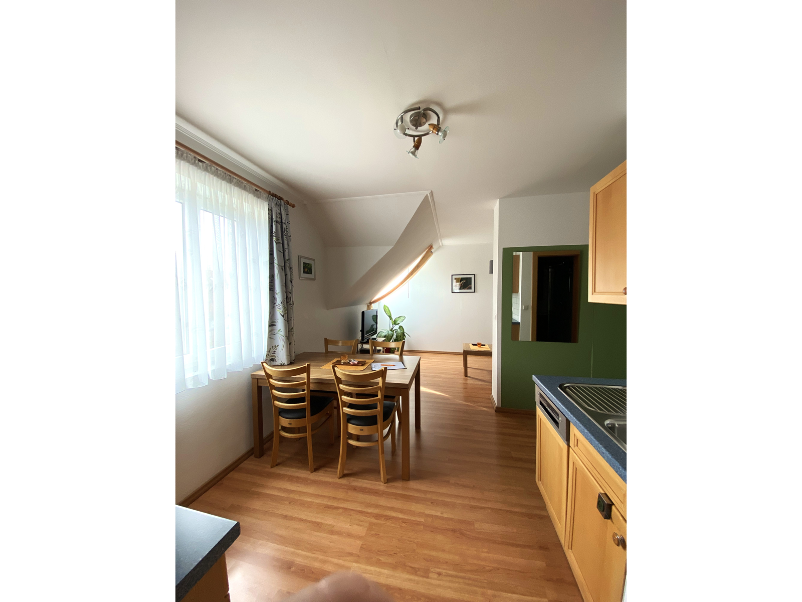 Pohľad do interiéru prázdninového bytu s jedálenským stolom, stoličkami a kuchynským kútom.