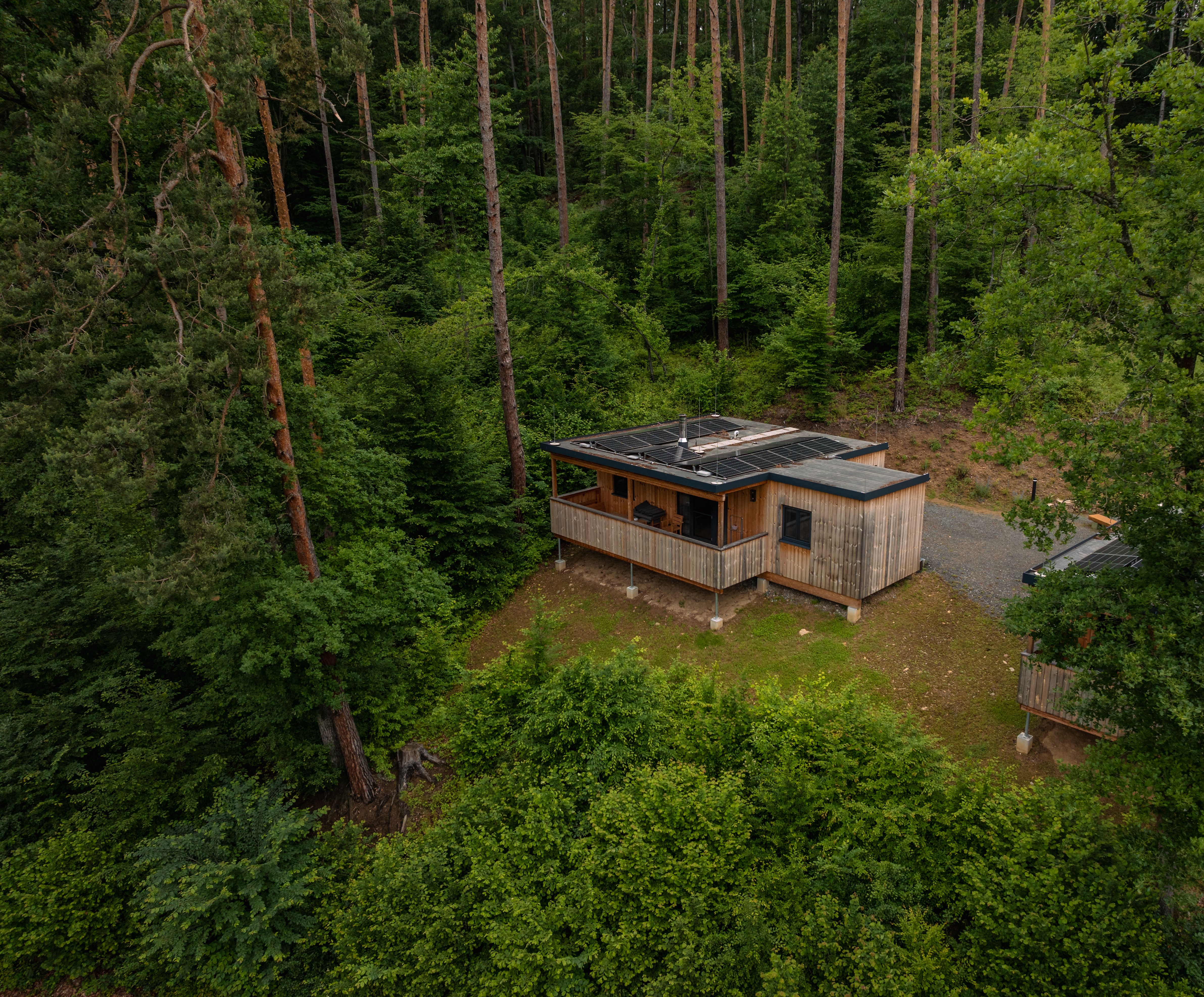 Letecký pohľad na zrúcaninu hradu pri jazere, obklopenú lesom a kopcami.