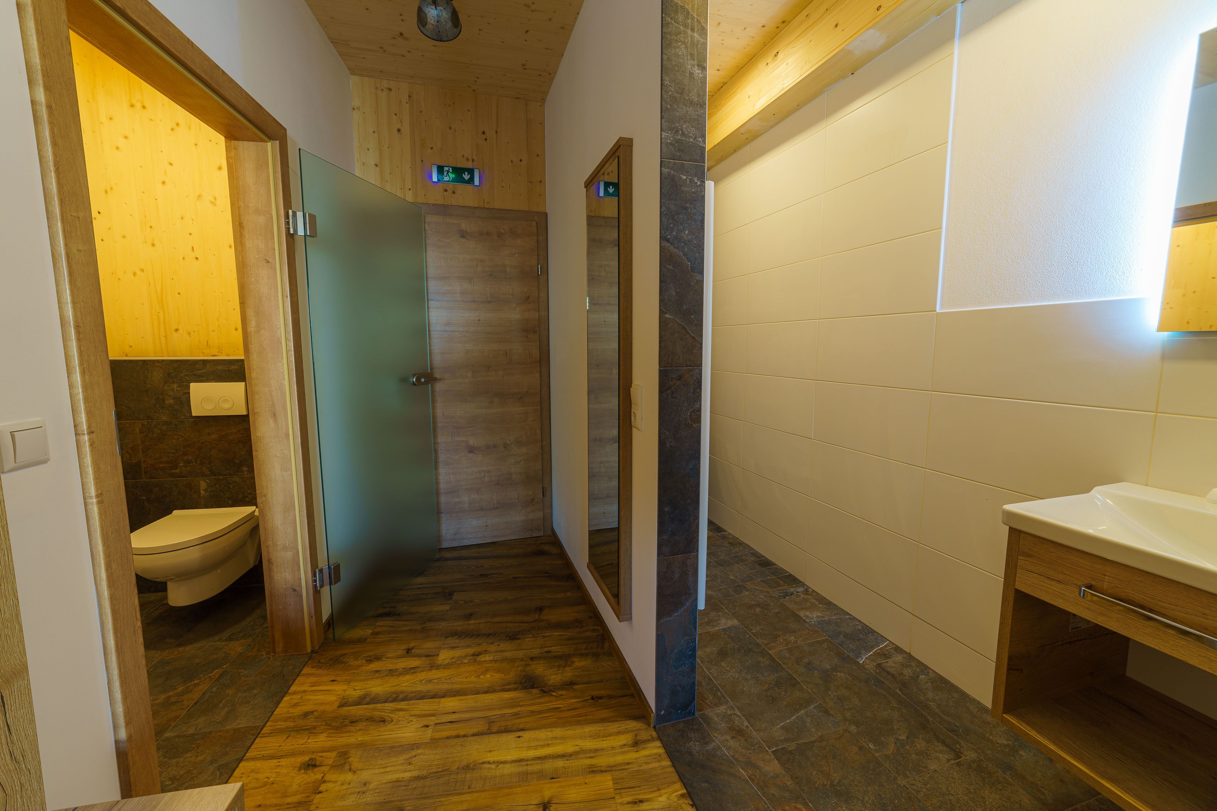 Moderná kúpeľňa s drevenými prvkami a sklenenými detailmi.