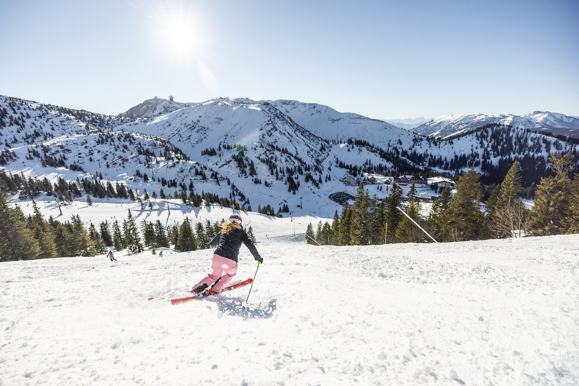 Die strahlende Wintersonne glitzert auf dem frischen Schnee, während eine Skifahrerin elegant die Piste hinuntergleitet. Umgeben von den majestätischen Ybbstaler Alpen, vermittelt die Szene ein Gefühl von Freiheit und Abenteuer. Hier wird der Winter zum Erlebnis für alle, die die verschneiten Berge lieben.