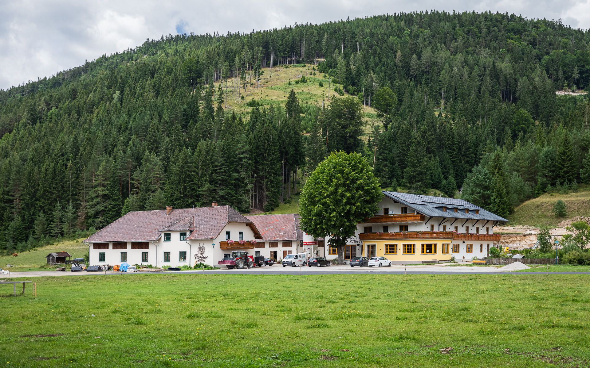 Gasthof Furtner pred zalesneným kopcom.