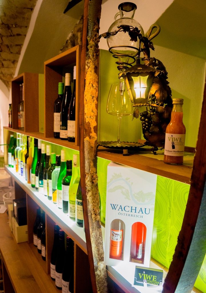 Polica s fľašami vína a dekoráciami vo vinotéke.
