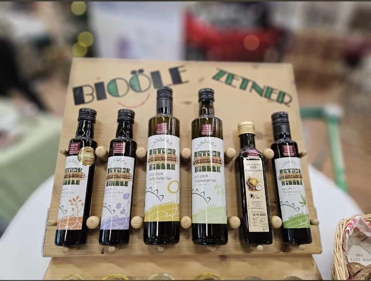 Päť fliaš bio oleja na drevenom stojane s nápisom "Bioöle Zeiner".