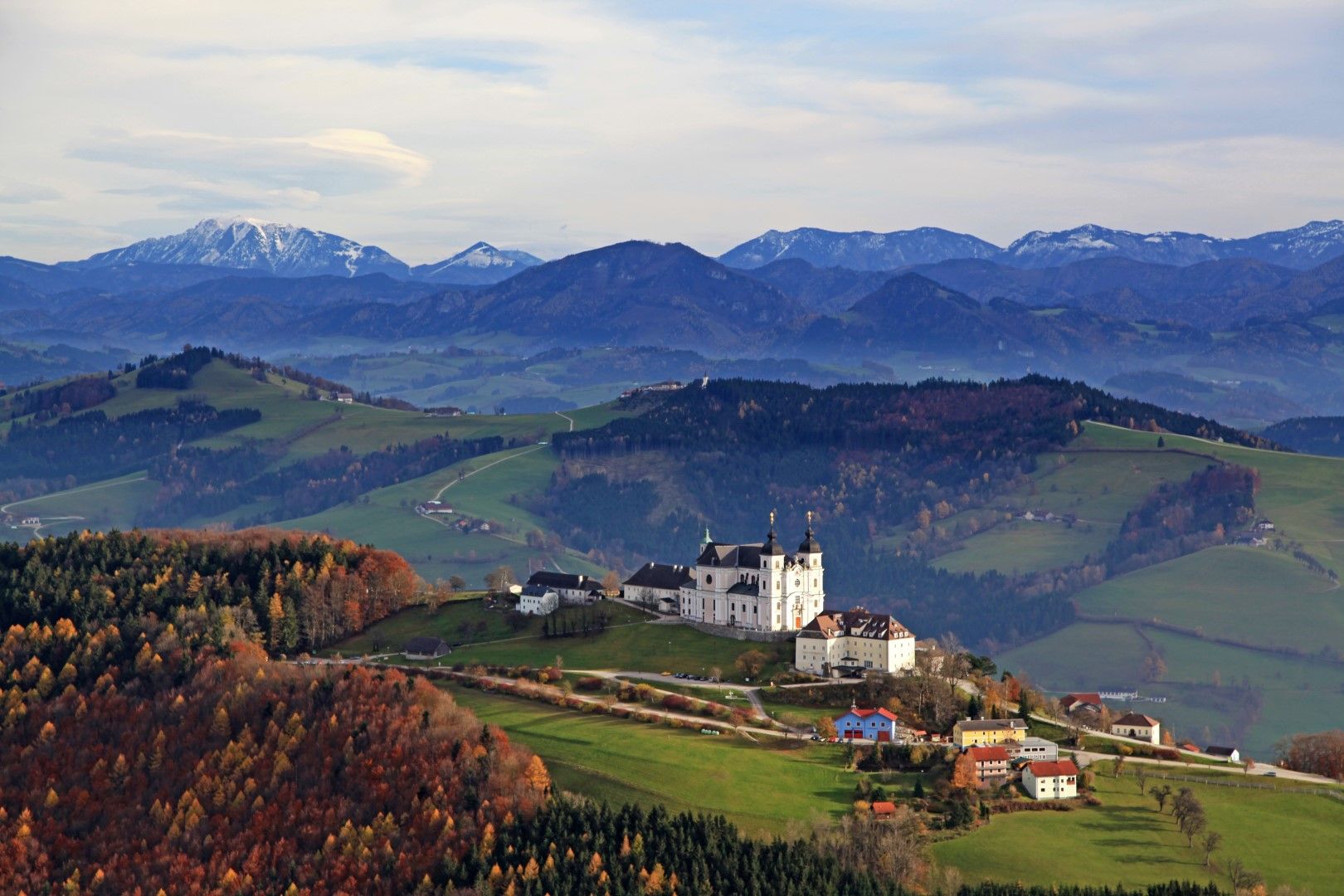 Panoramatický pohľad na Mostviertel s bazilikou Sonntagberg v popredí a horami v pozadí.