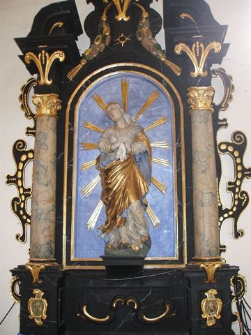 Baroková socha Madony Bolestnej v bohato zdobenom oltári.