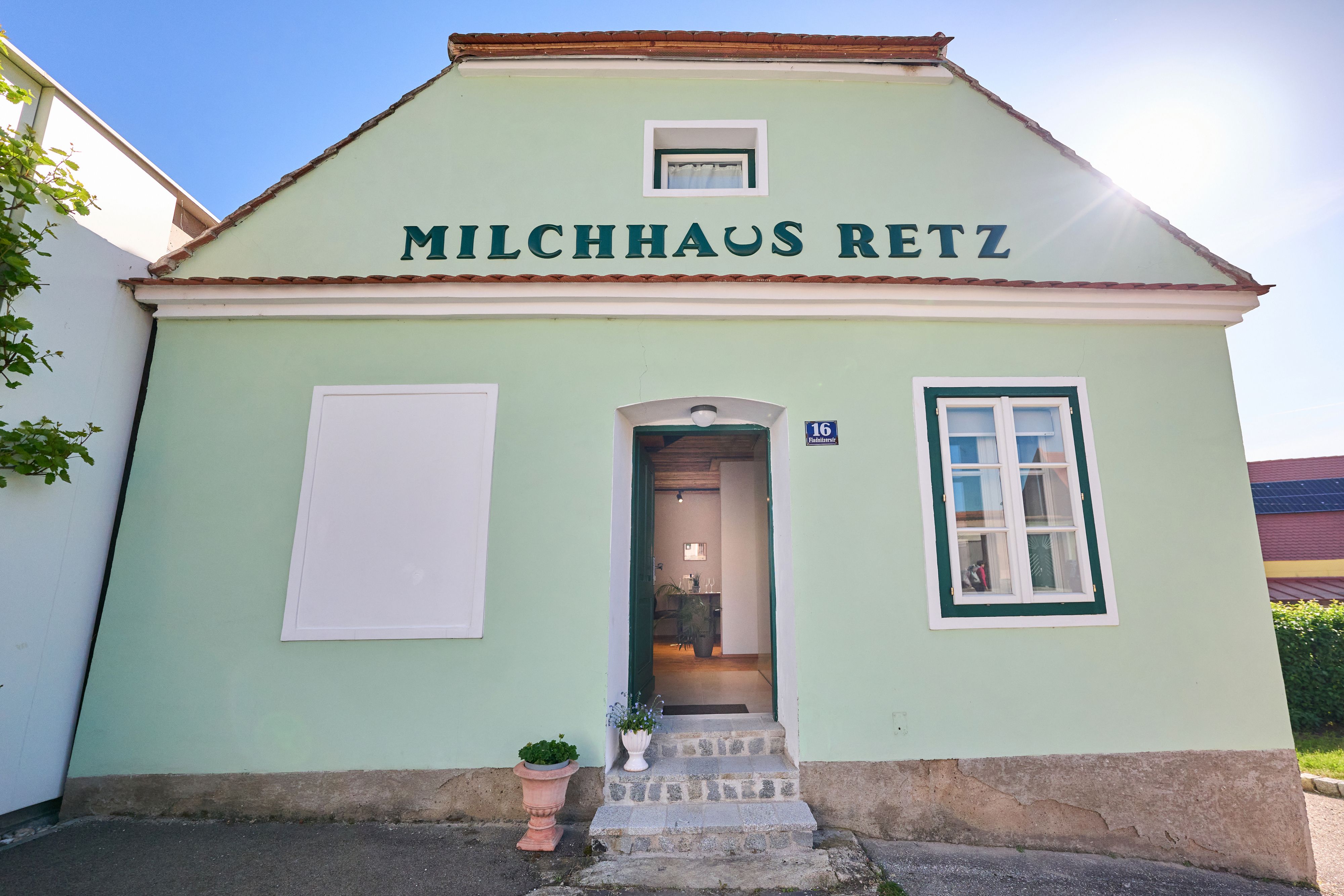 Zelená budova s nápisom "Milchhaus Retz" a otvorenými dverami.
