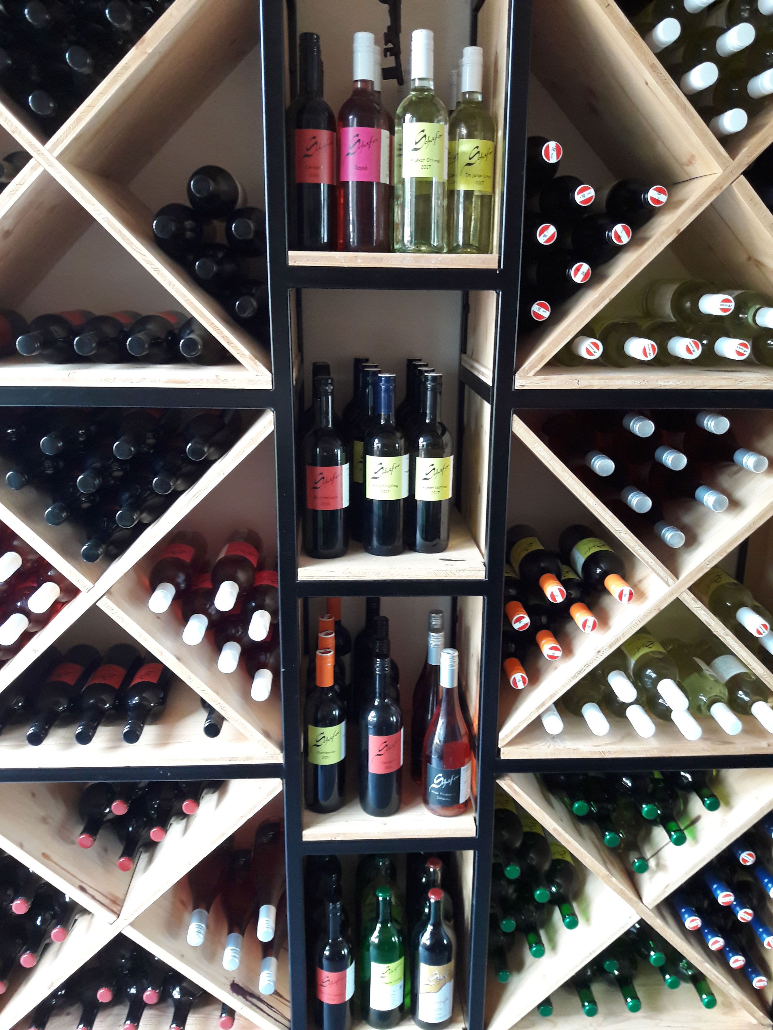 Fľaše na víno na drevenej polici s diagonálnymi policami.