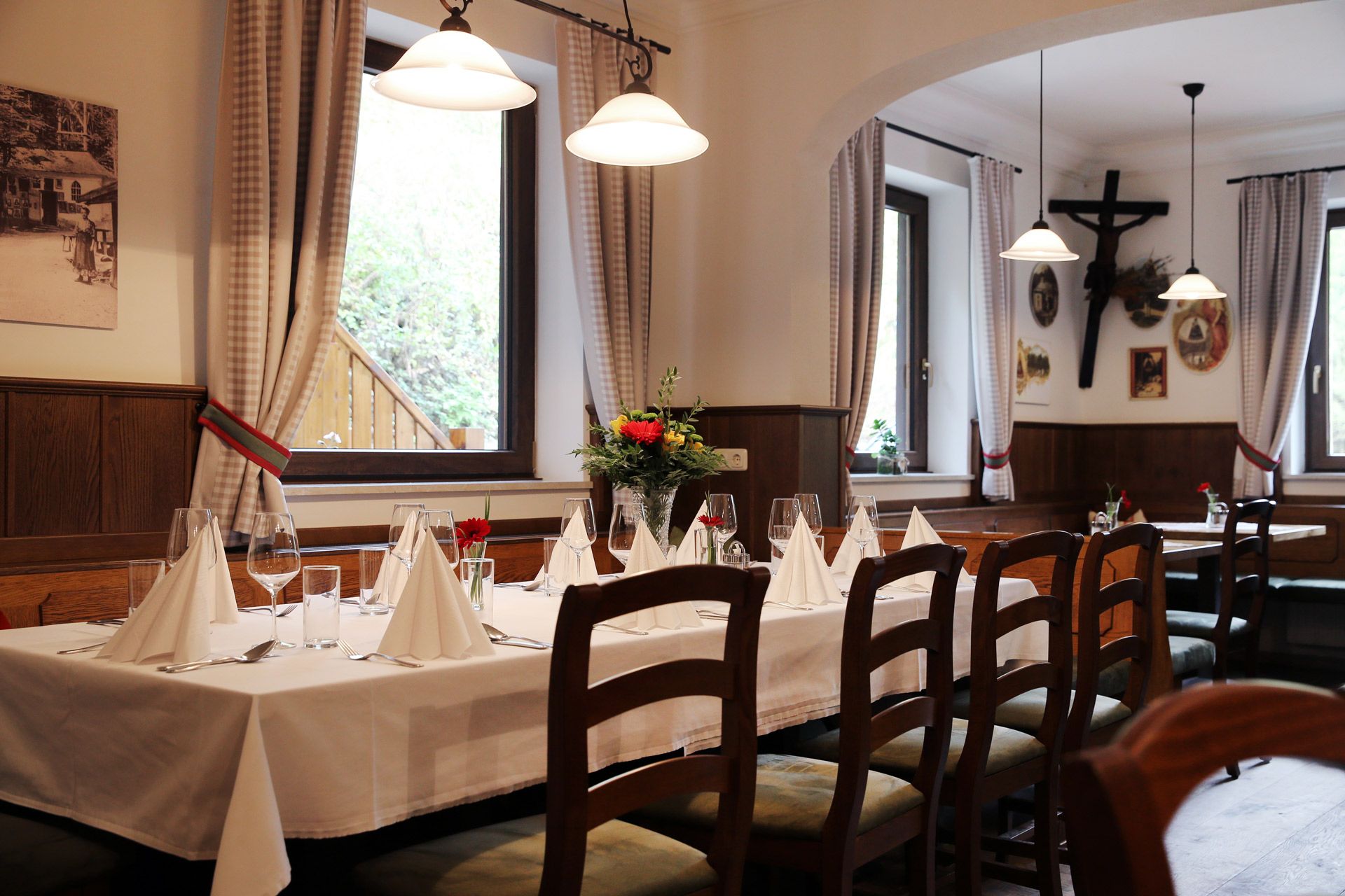 Interiér útulného hostinca s prestretým stolom, dreveným nábytkom a dekoráciami na stenách.