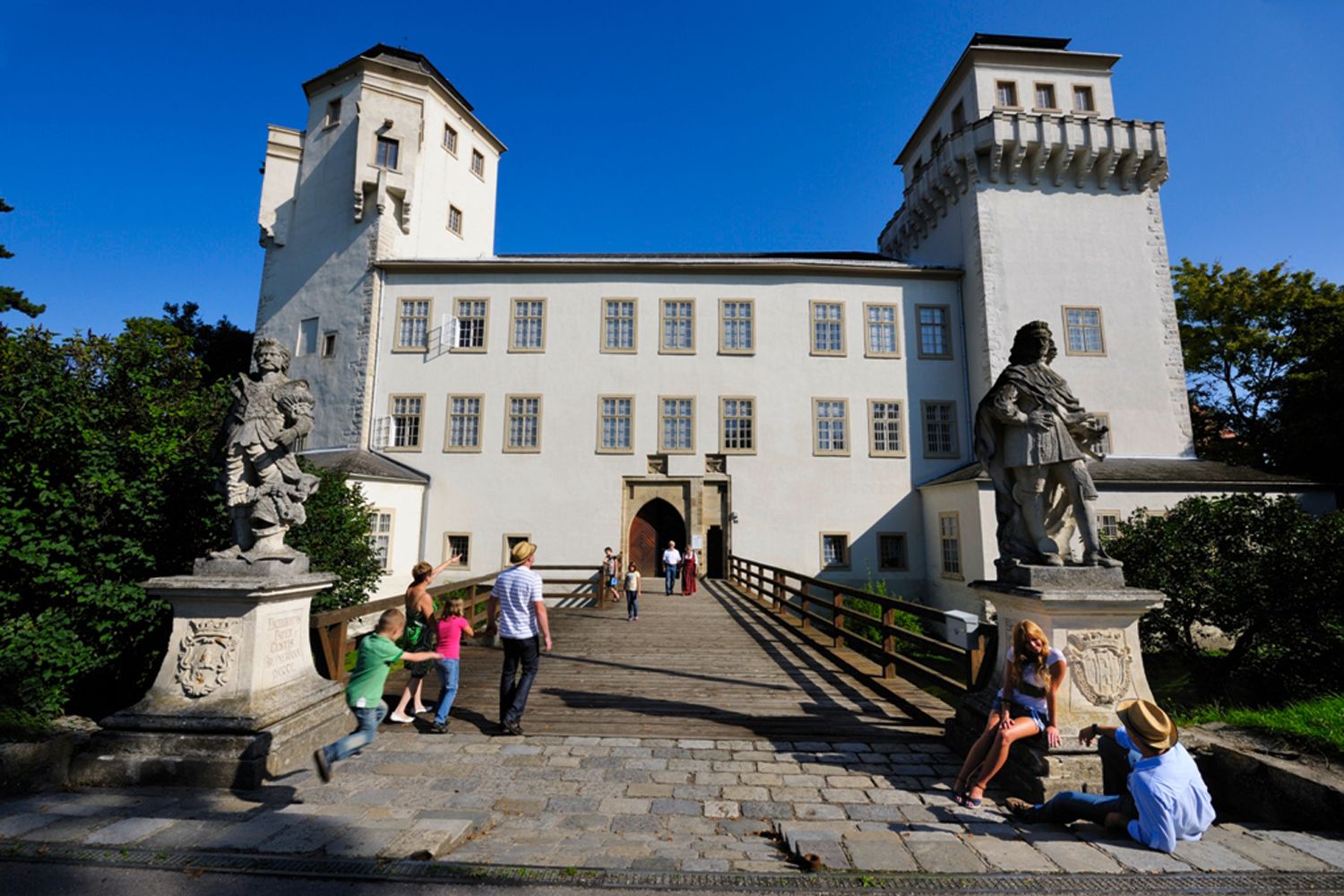 Hrad Asparn/Zaya s návštevníkmi a sochami v popredí.