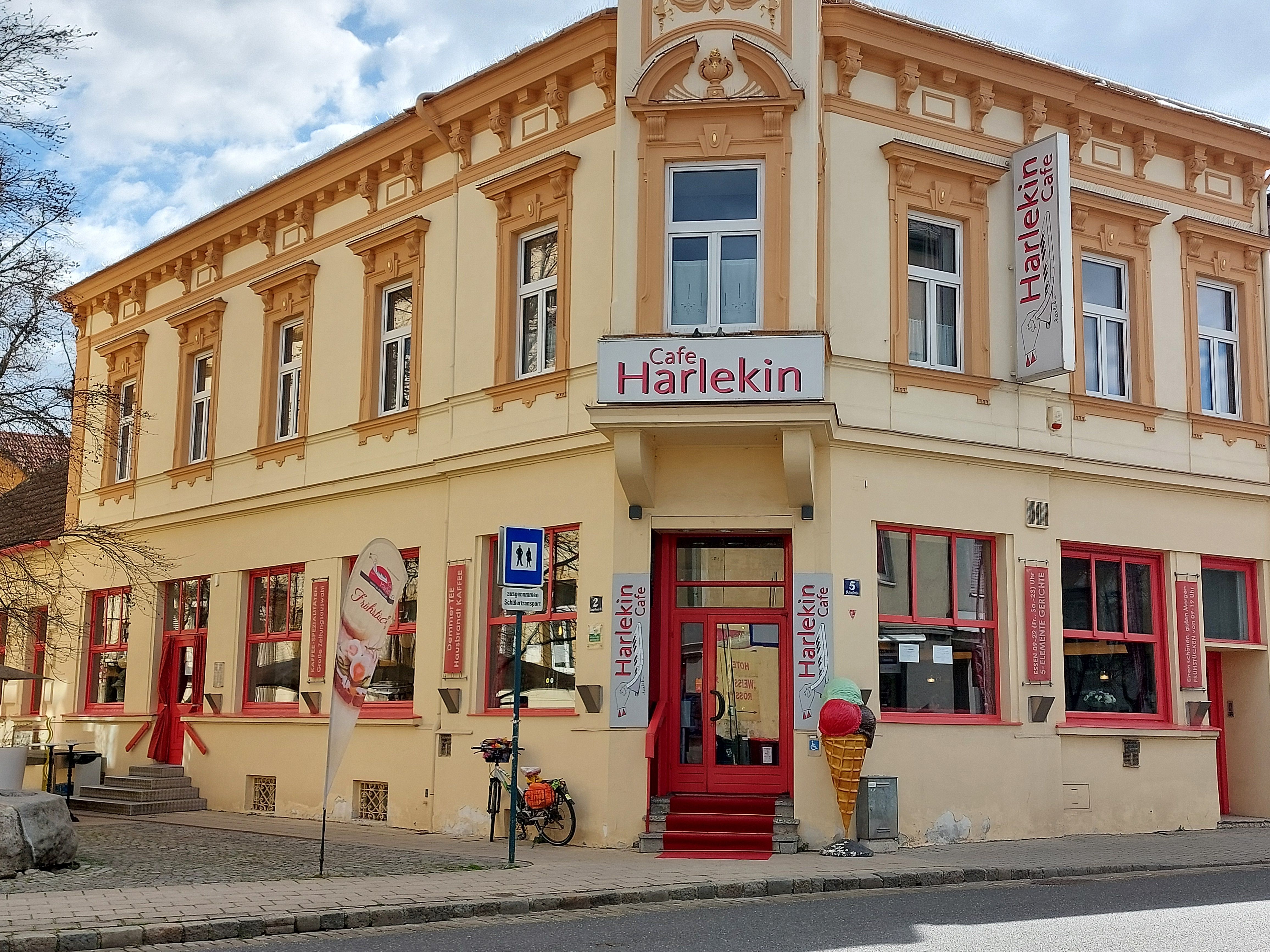 Exteriérový pohľad na kaviareň Restaurant Harlekin so žltou fasádou a červenými oknami.