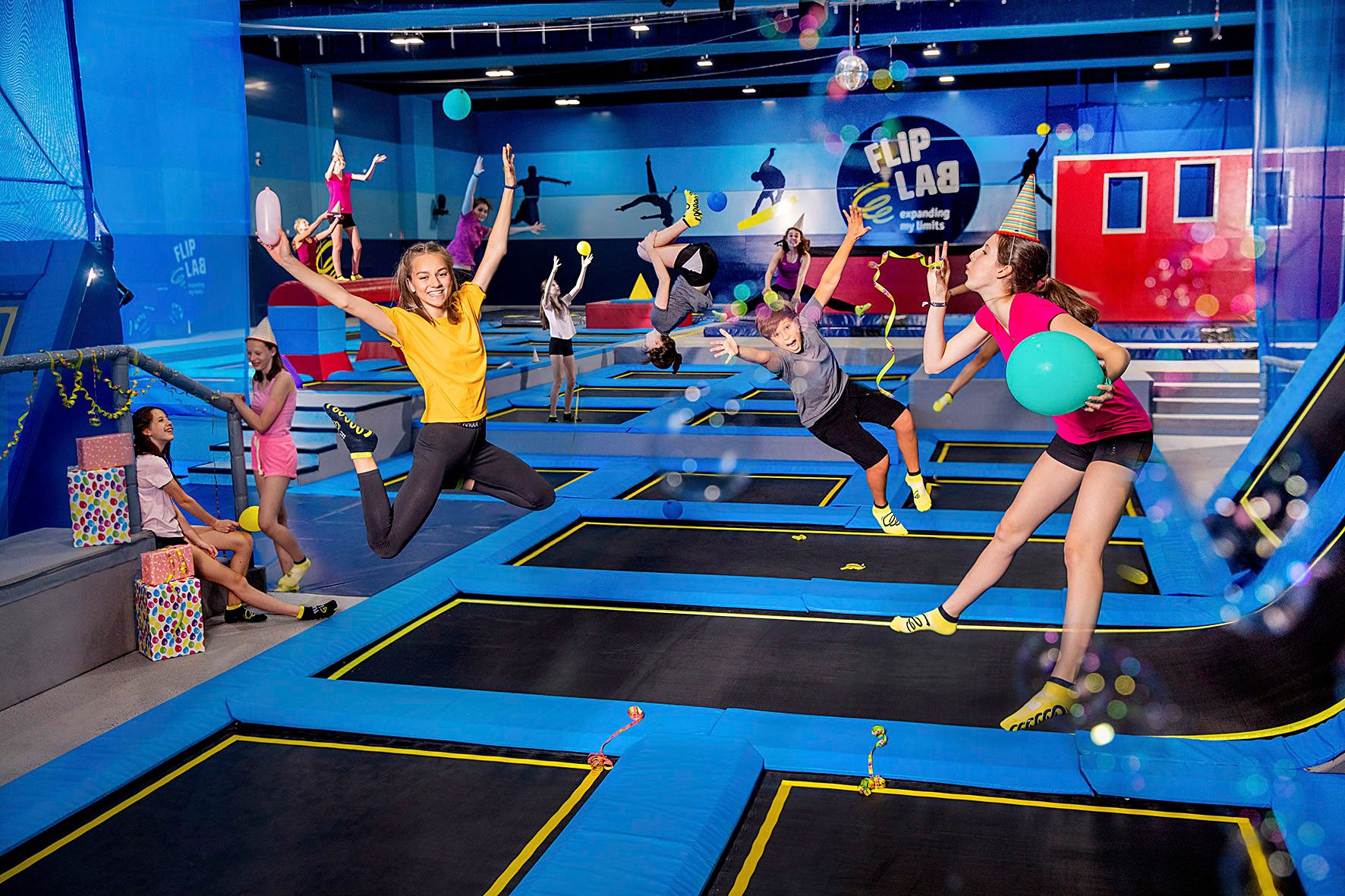 Ľudia skáču na trampolínach v hale s logom "Flip Lab".