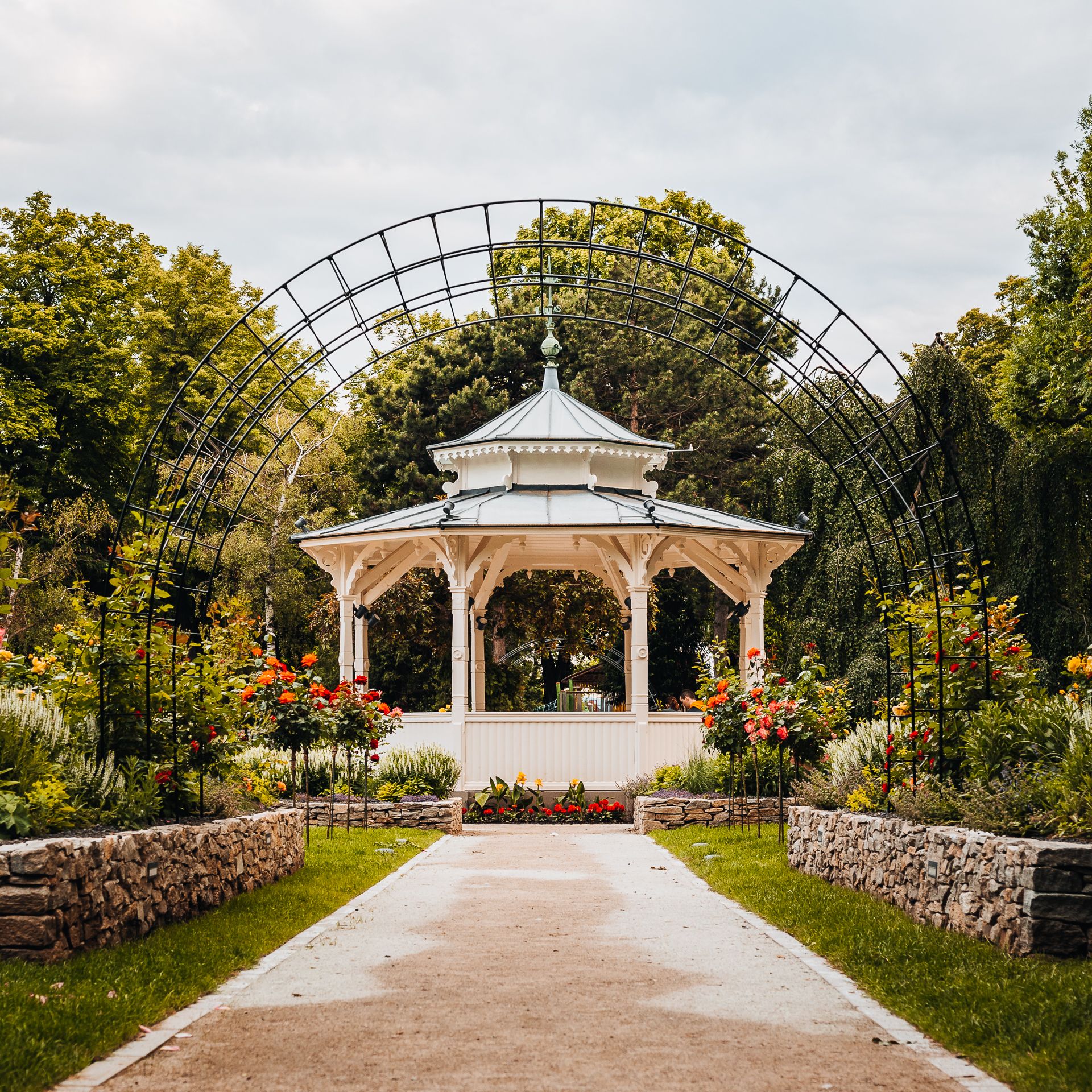 Zelený mestský park s romantickým pavilónom, ružovou záhradou a klenutým oblúkom