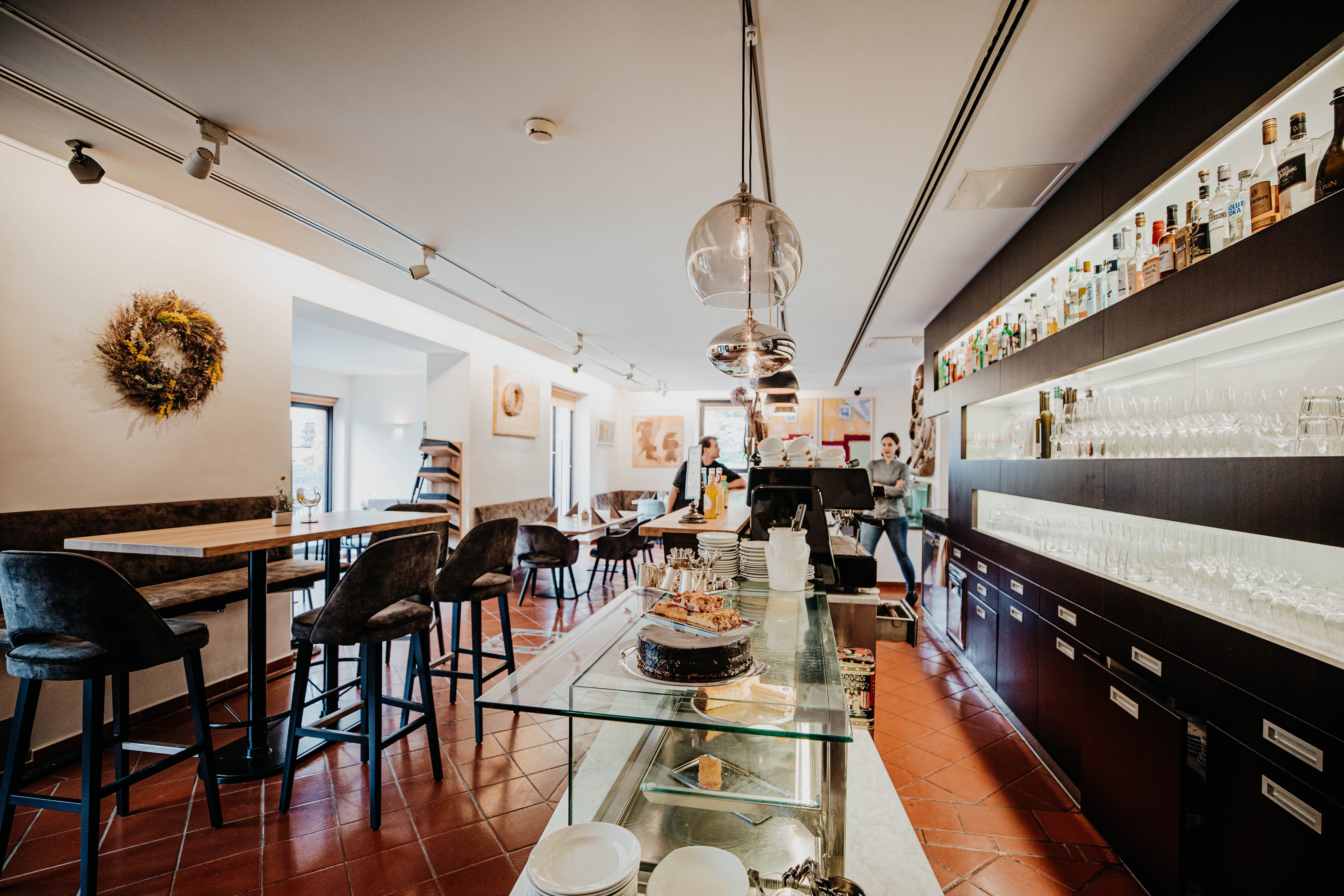 Pohľad do interiéru modernej reštaurácie s barom, stolmi a stoličkami.