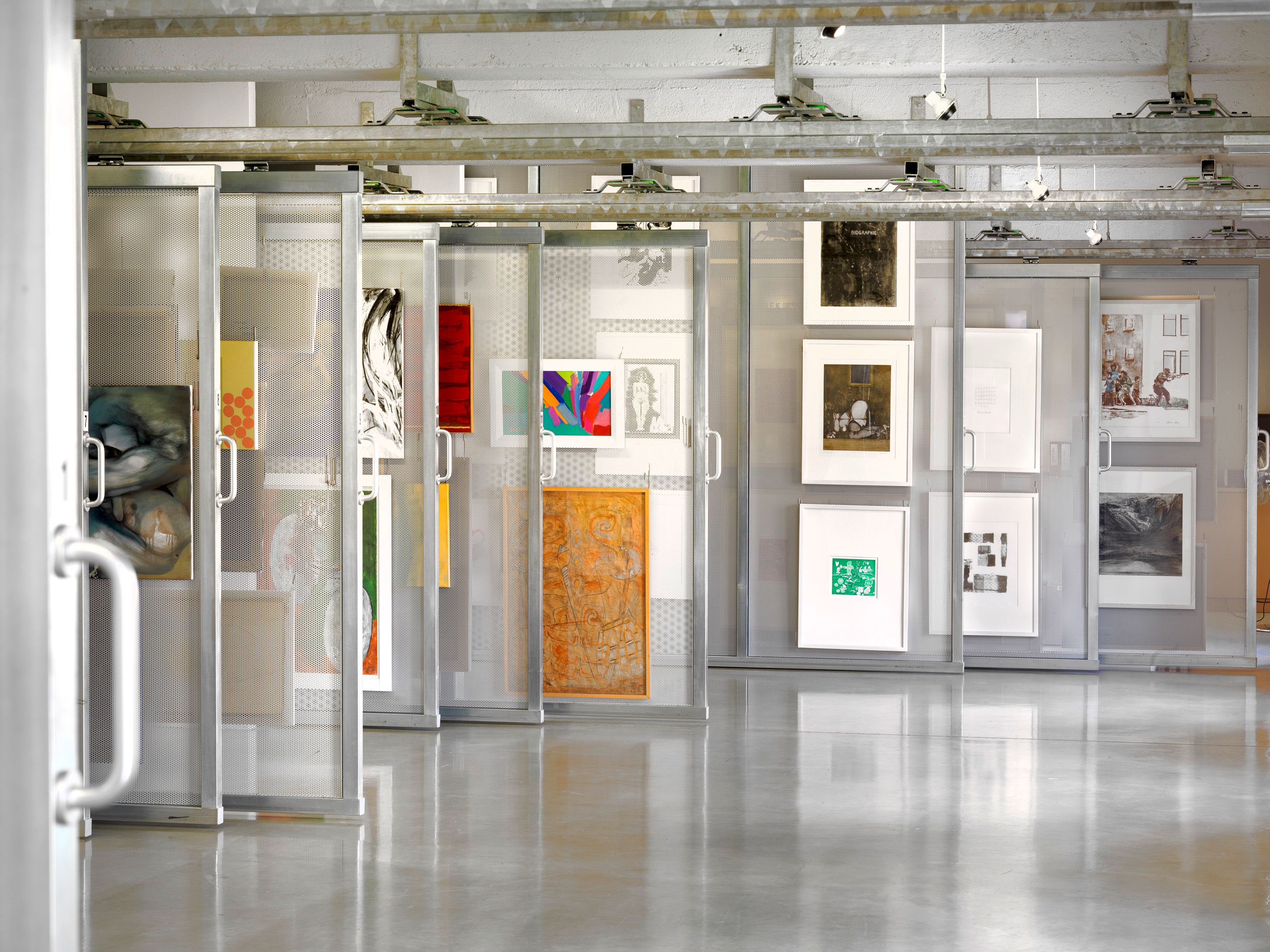 Pohľad do interiéru umeleckej knižnice s umeleckými dielami na pohyblivých policiach.