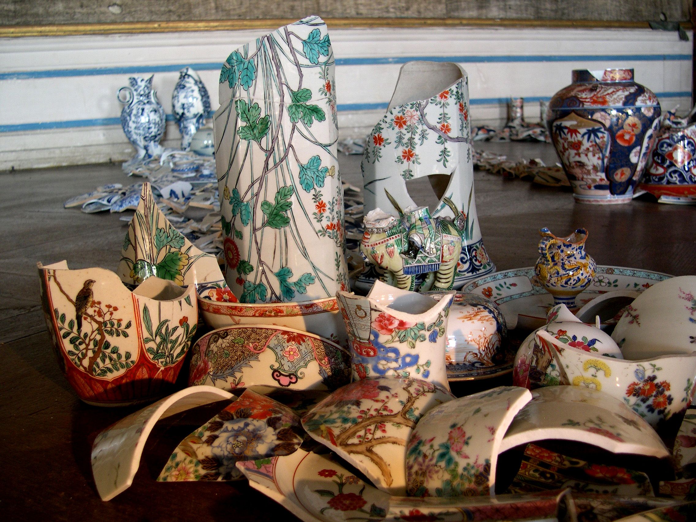 Rozbité kúsky porcelánu s farebnými vzormi usporiadané na podlahe.