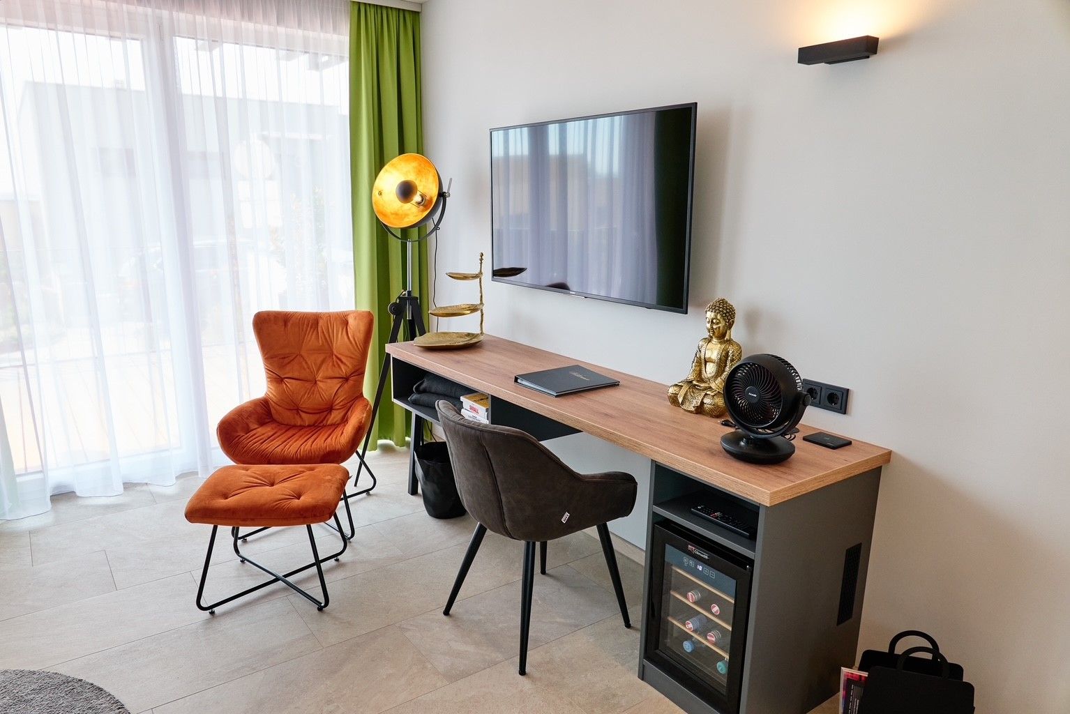 Obývacia izba s kreslom, písacím stolom, sochou Budhu a televízorom.