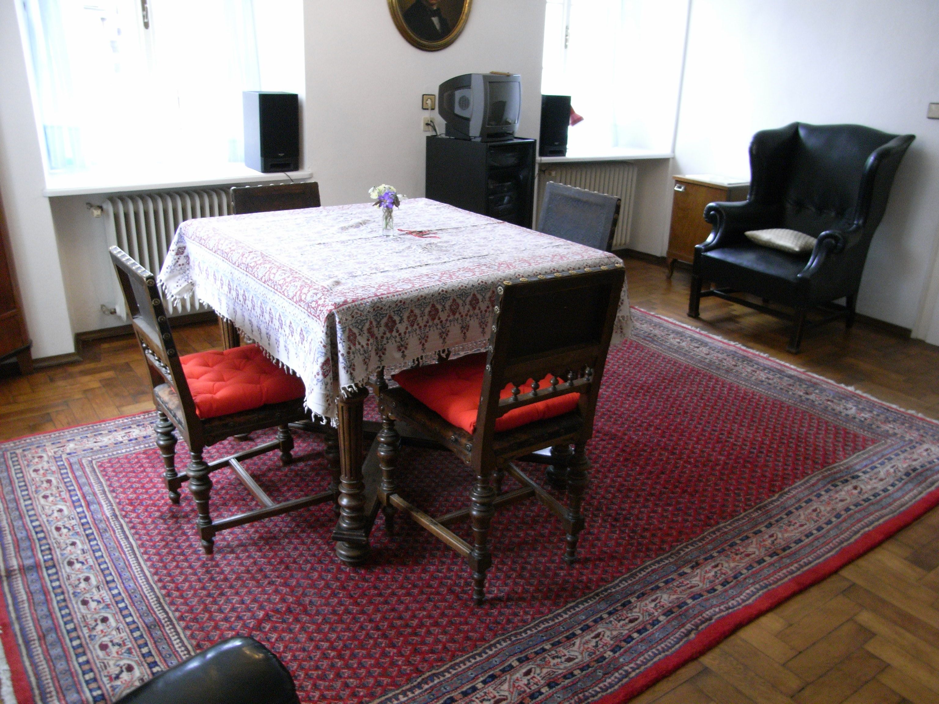 Obývacia izba so stolom, stoličkami a kobercom.